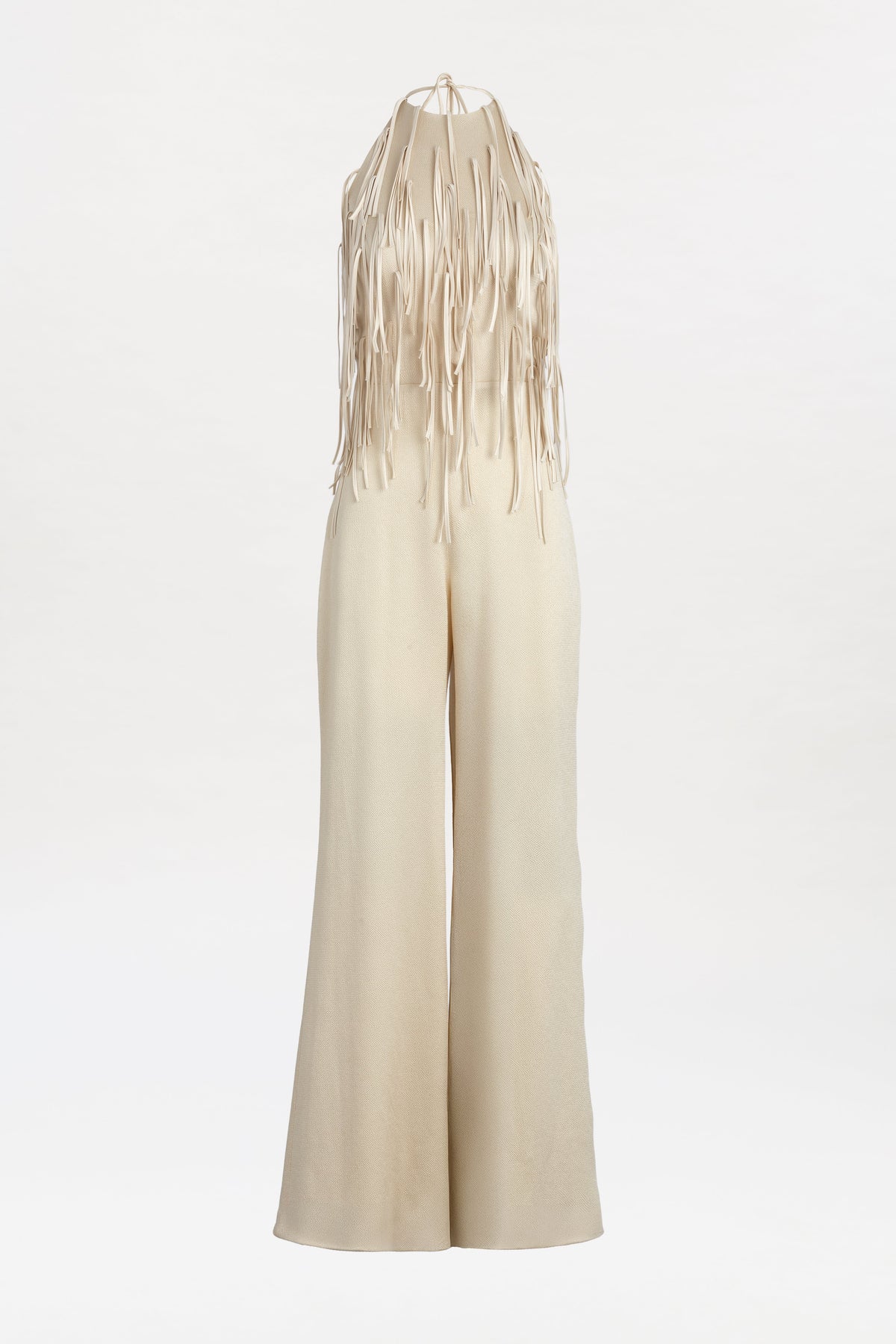 The Tulsi Jumpsuit is a cream-colored, sleeveless piece featuring flared legs and fringe detailing cascading from the neckline and upper bodice, shown against a plain white background.