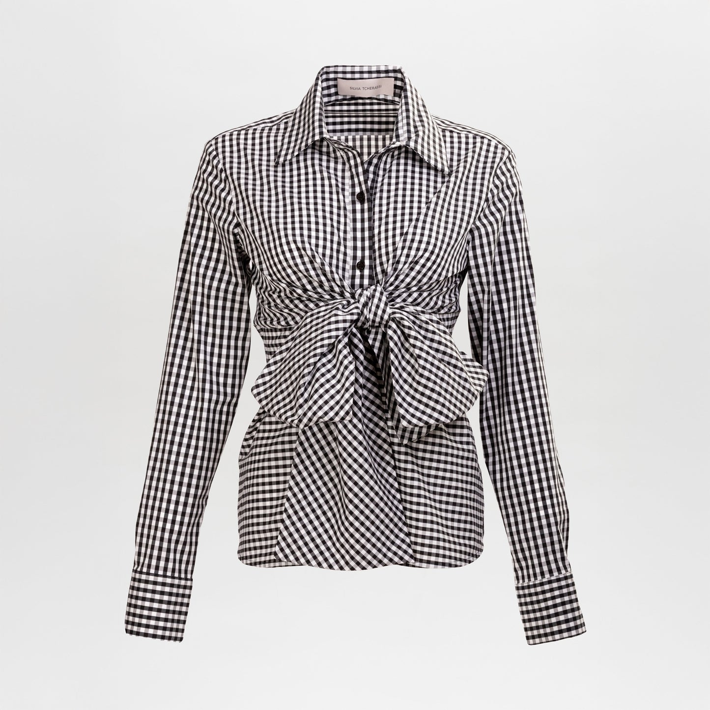 The Mercury Blouse is a black and white gingham long-sleeve shirt featuring a pointed collar and a front waist tie, shown on a plain background.