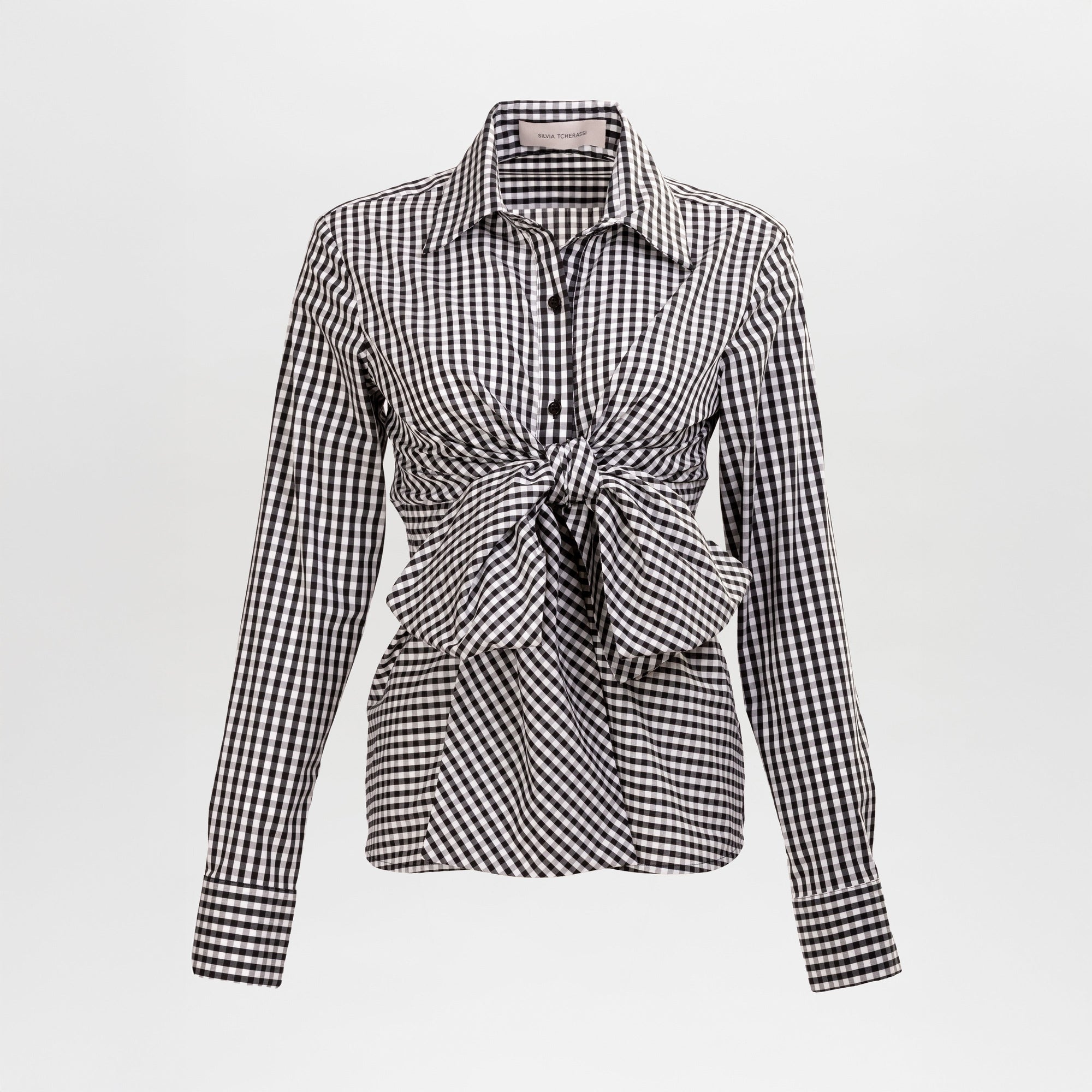 The Mercury Blouse is a black and white gingham long-sleeve shirt featuring a pointed collar and a front waist tie, shown on a plain background.