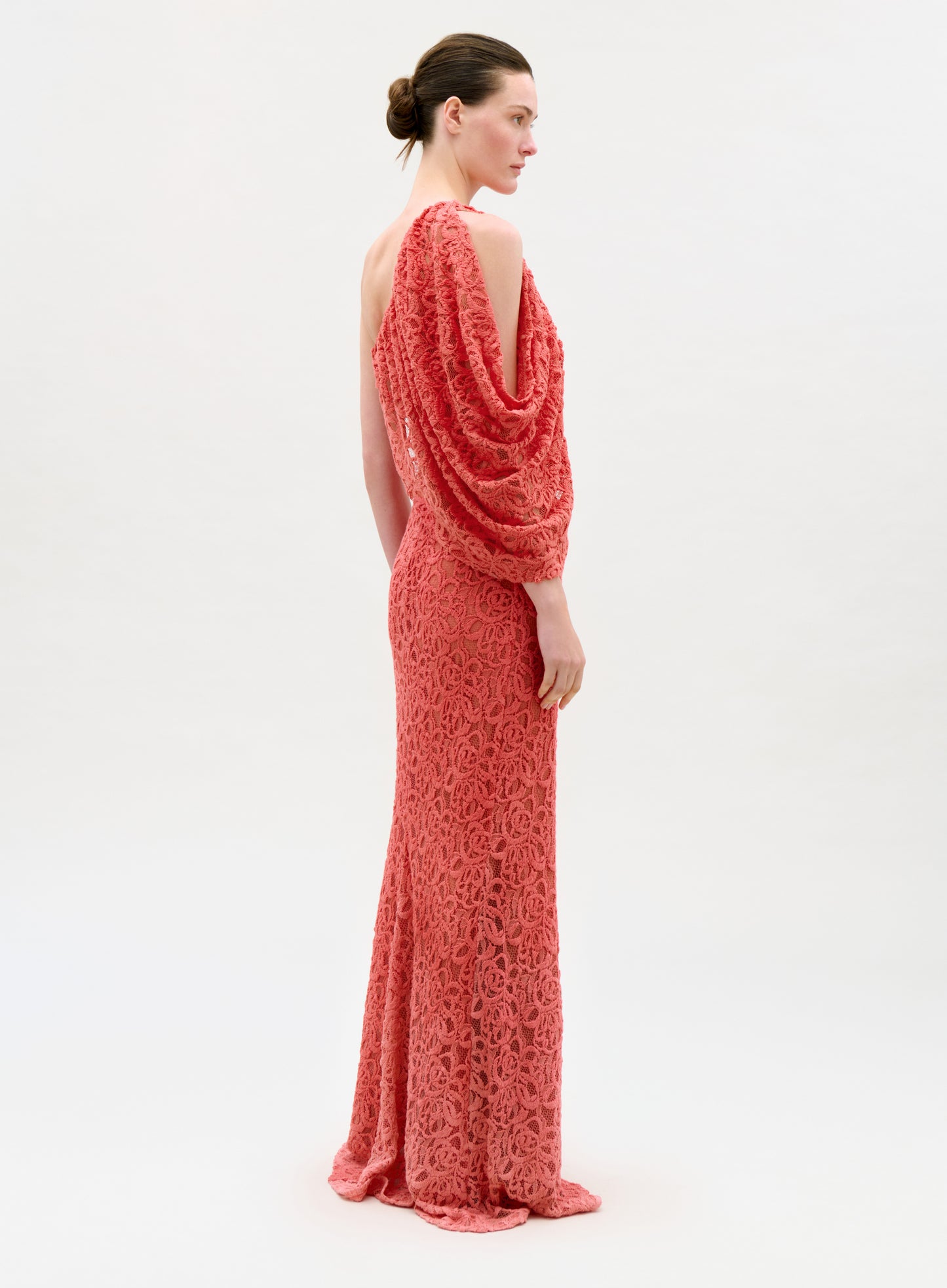 Woman wearing a coral one-shoulder evening gown on a white background