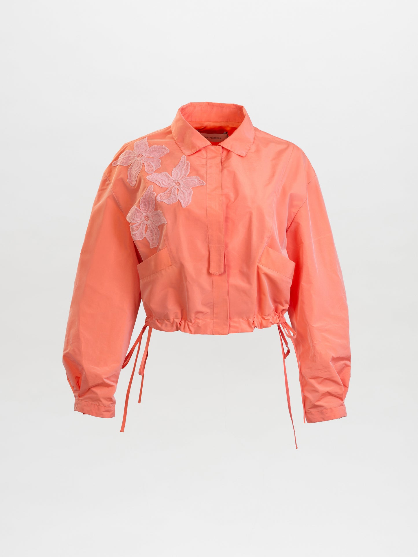 Coral jacket with lace details on a light gray background