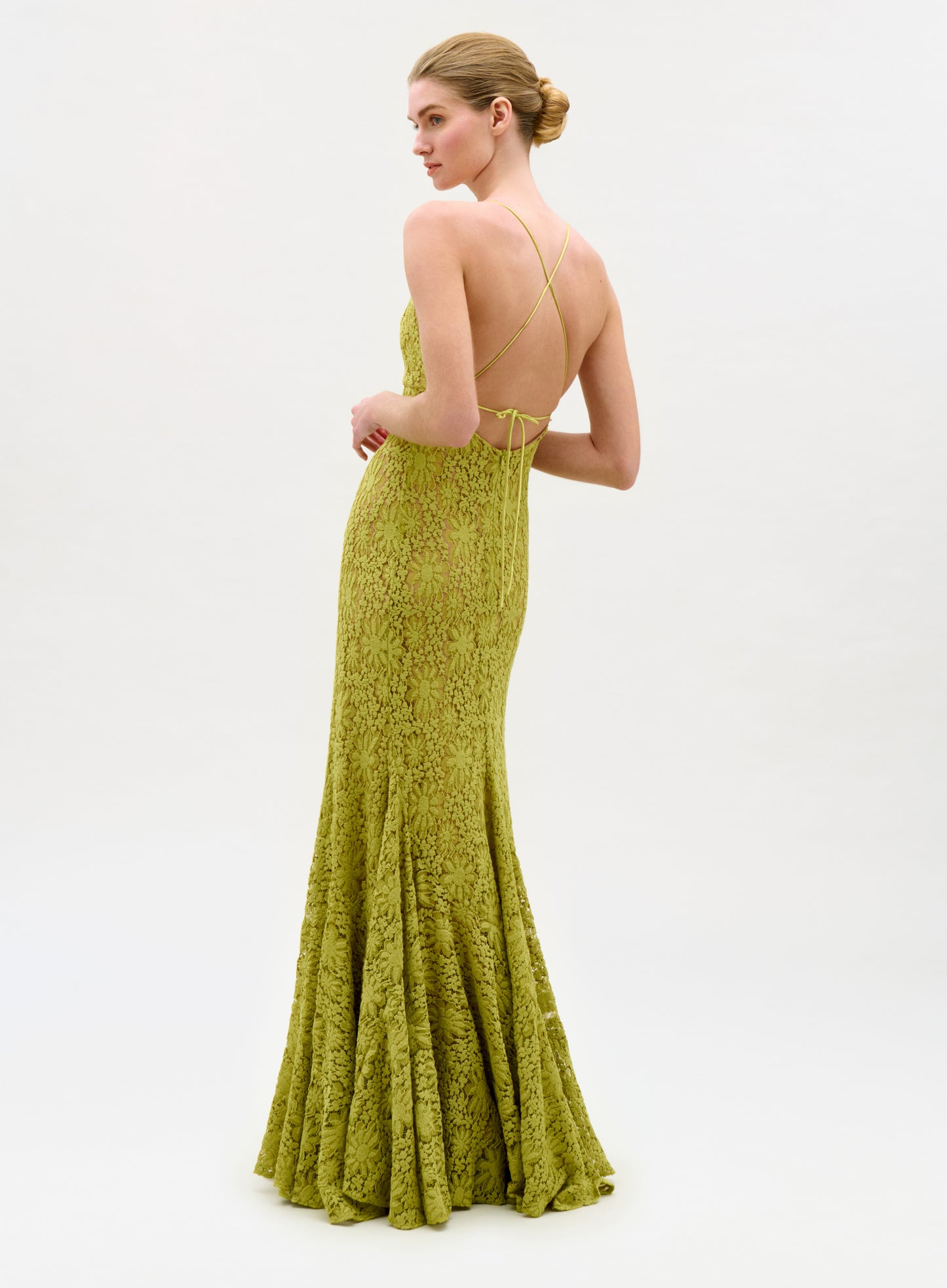 Woman wearing a green lace evening gown on a white background