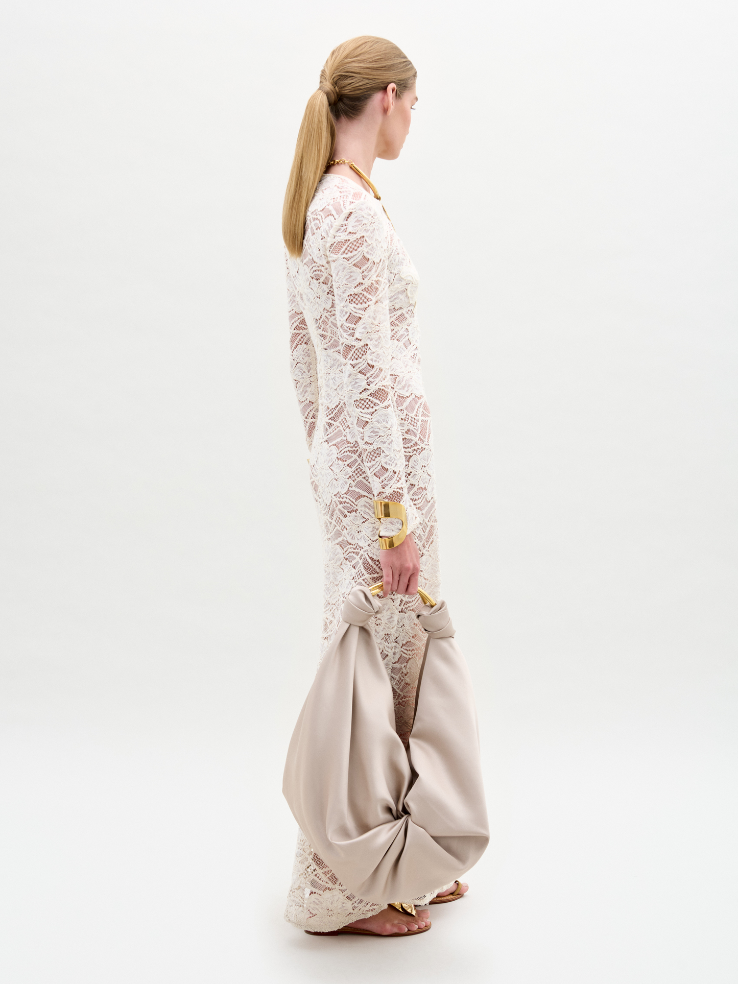 Woman wearing a white lace dress with beige pants on a white background