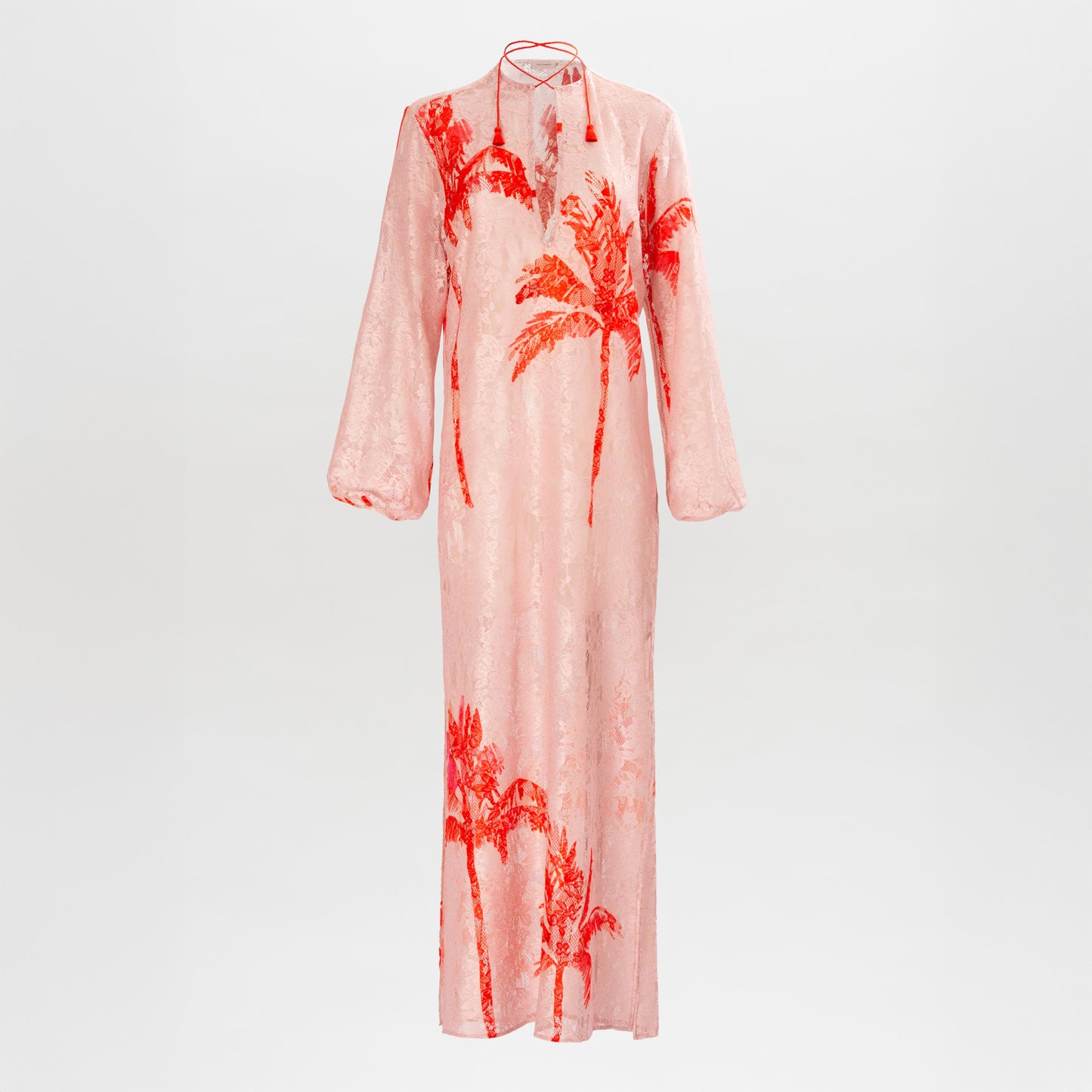 The Mayfair Tunic is a long, light pink maxi with long sleeves, bold red palm tree prints, a high neckline with back tie strings, and a loose silhouette. Crafted from fine Italian textile for effortless style.