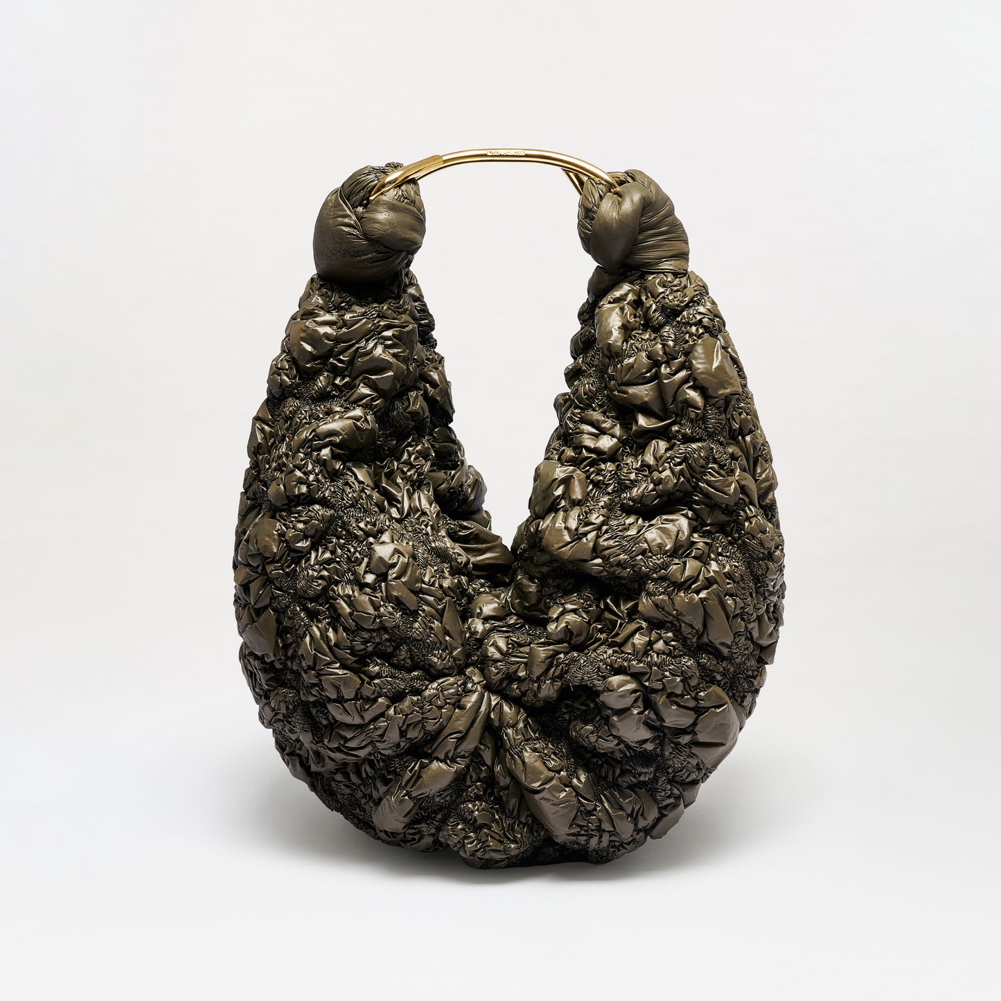 The Sofia Bag (Maxi), featuring a sculptural silhouette, dark textured material, gold-toned handle, and a twisted, crumpled design, sits upright against a plain white background.