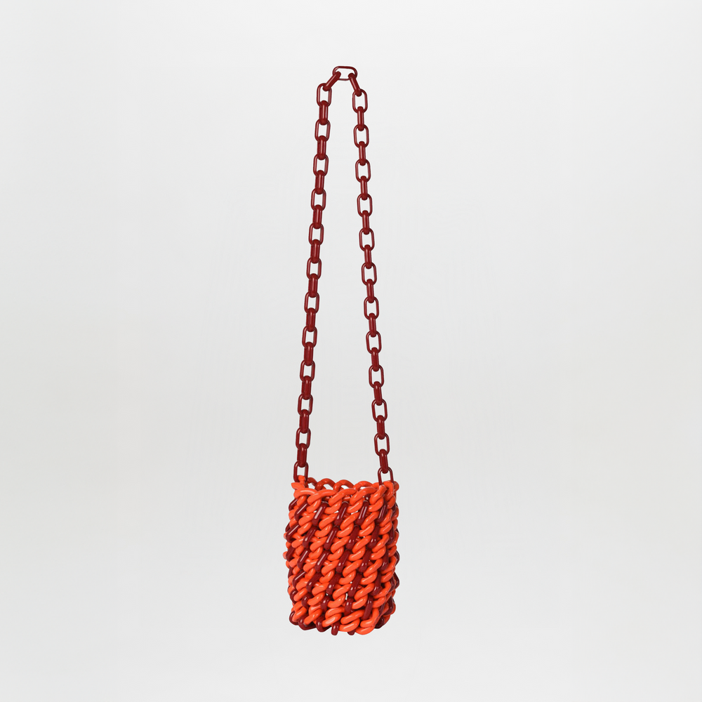 The Anise Bag Red / Burgundy is a small crossbody handbag with a chunky red resin ring chain strap and an orange woven body, shown against a plain white background.