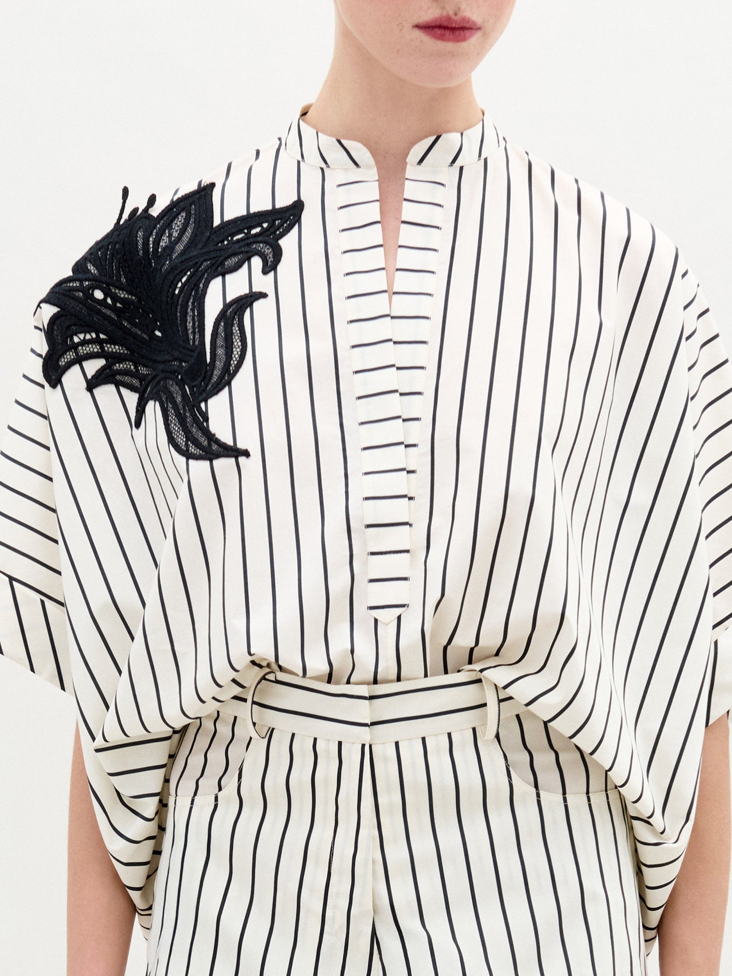 A person wearing the Daia Blouse in color Black White Stripes on a white background.