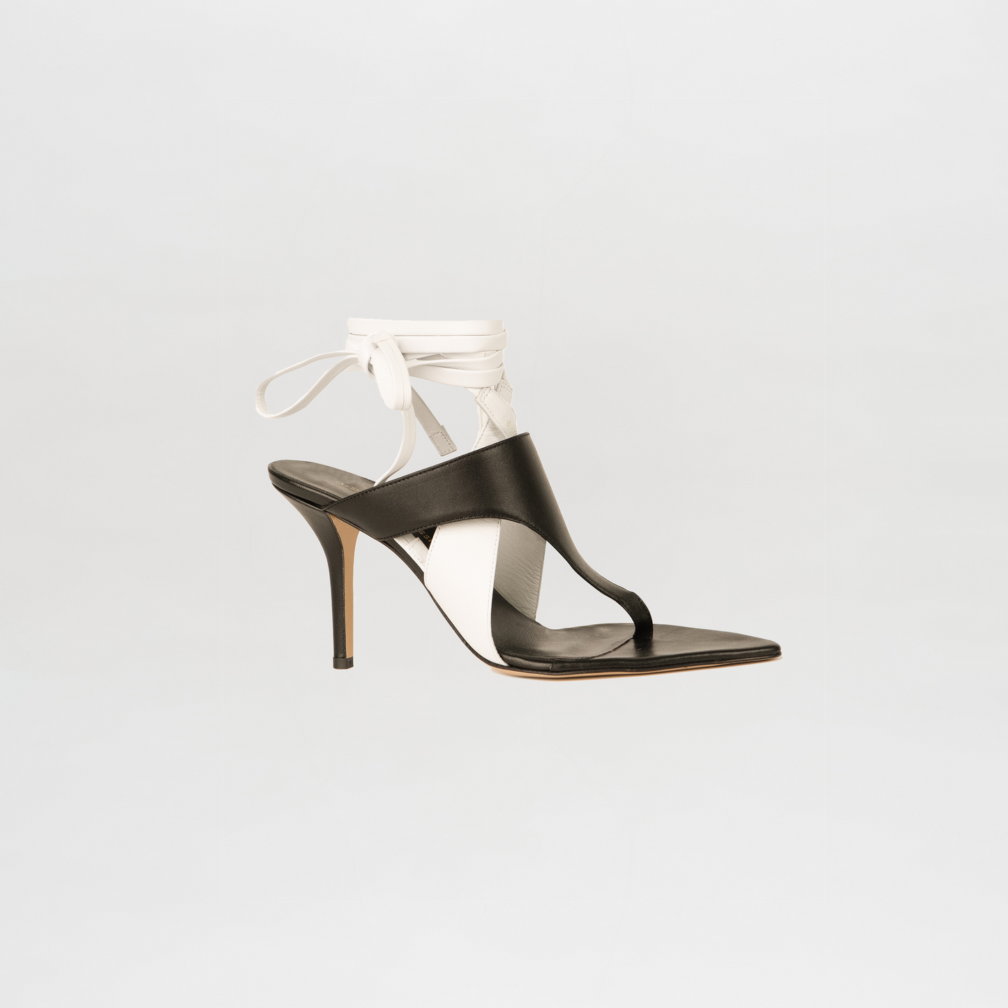 Black high-heeled sandal with white ribbon on a light gray background