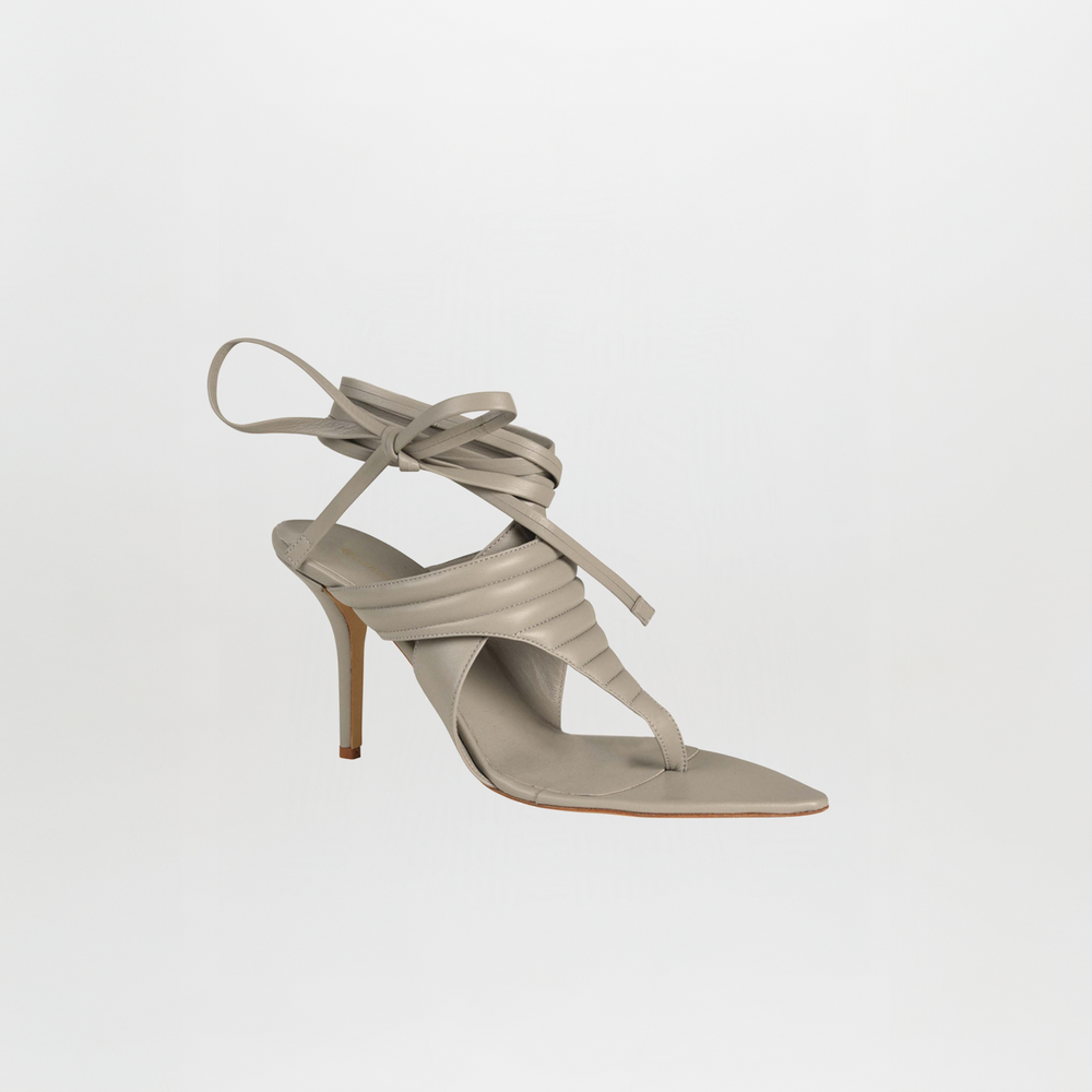 A grey Dalila heels sandal crafted from Italian calf leather, featuring a quilted toe-thong, square toe, padded upper, and long ankle wrap laces, displayed on a plain white background.