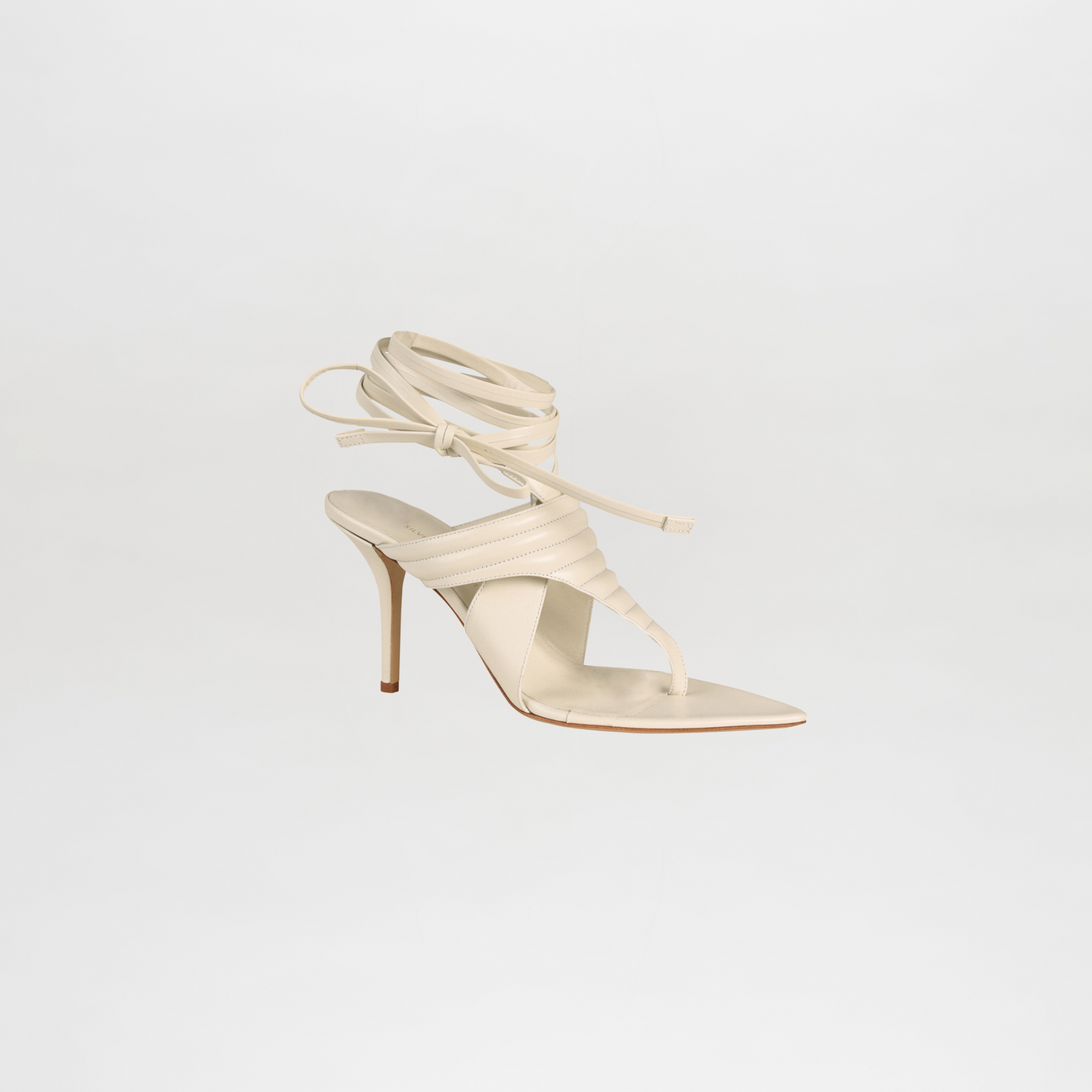 White strappy high-heeled shoe on a light gray background