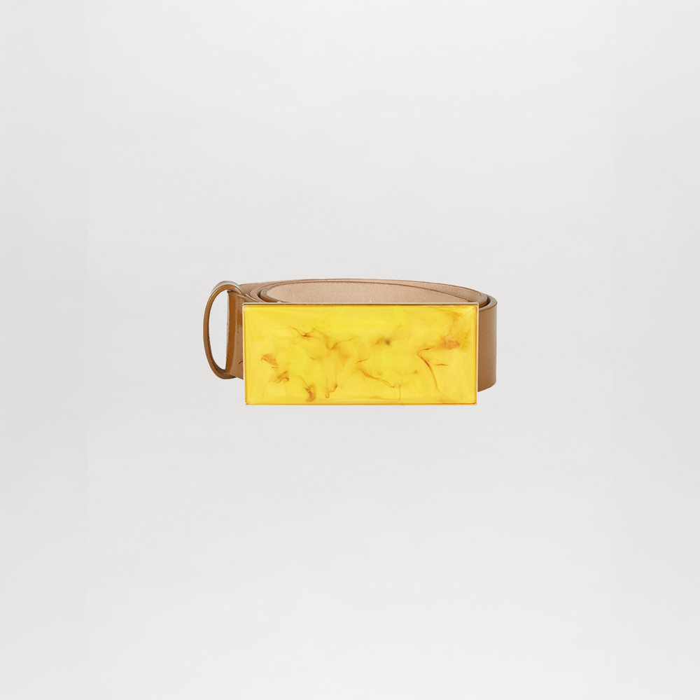 The Dora Belt Amber is a tan leather statement belt with a large rectangular yellow marbled buckle, shown against a plain white background.