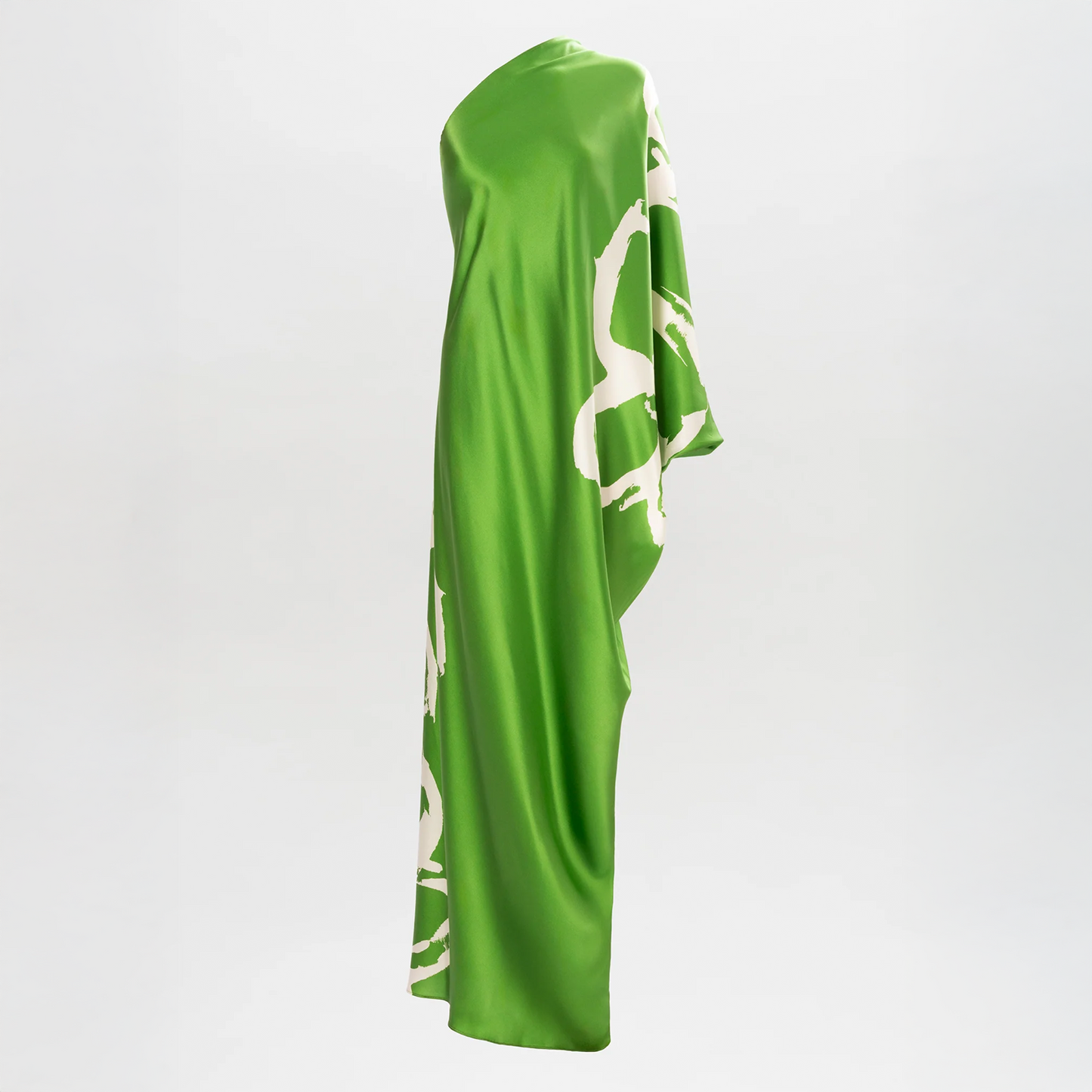 The Inu Tunic, crafted from luxurious green Italian satin with an asymmetrical neckline and abstract white print, is elegantly draped against a plain white background.
