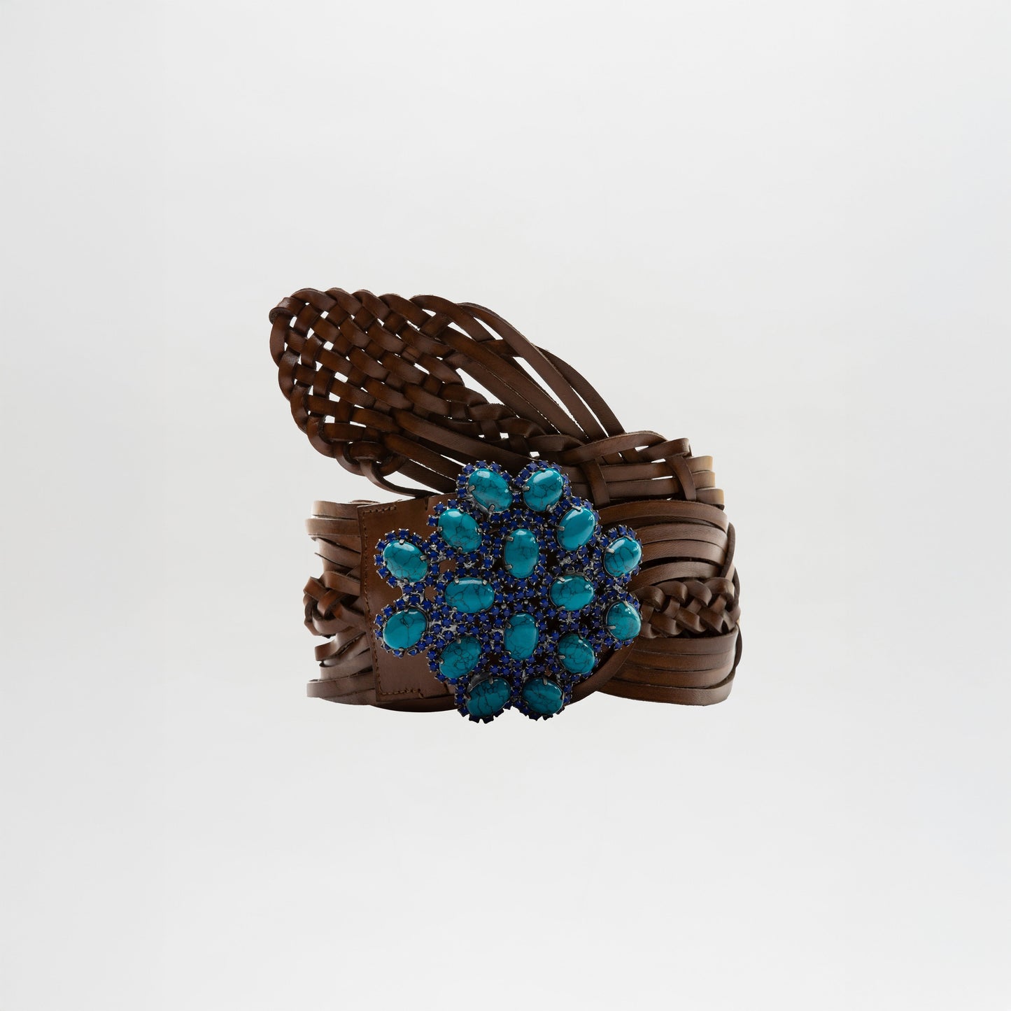 The Eines Belt, featuring brown Italian leather in a braided design and a large ornate blue gemstone buckle, is shown against a plain white background.