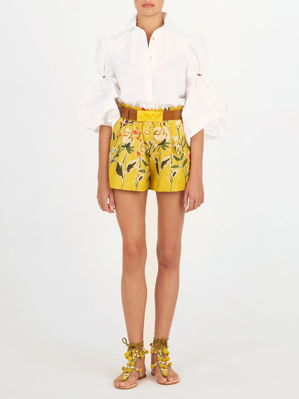 The Enio Blouse White is a long-sleeve shirt dress with puffed sleeves, a high collar, belted waist with a rectangular buckle, and delicate floral embroidery, shown on a plain white background.