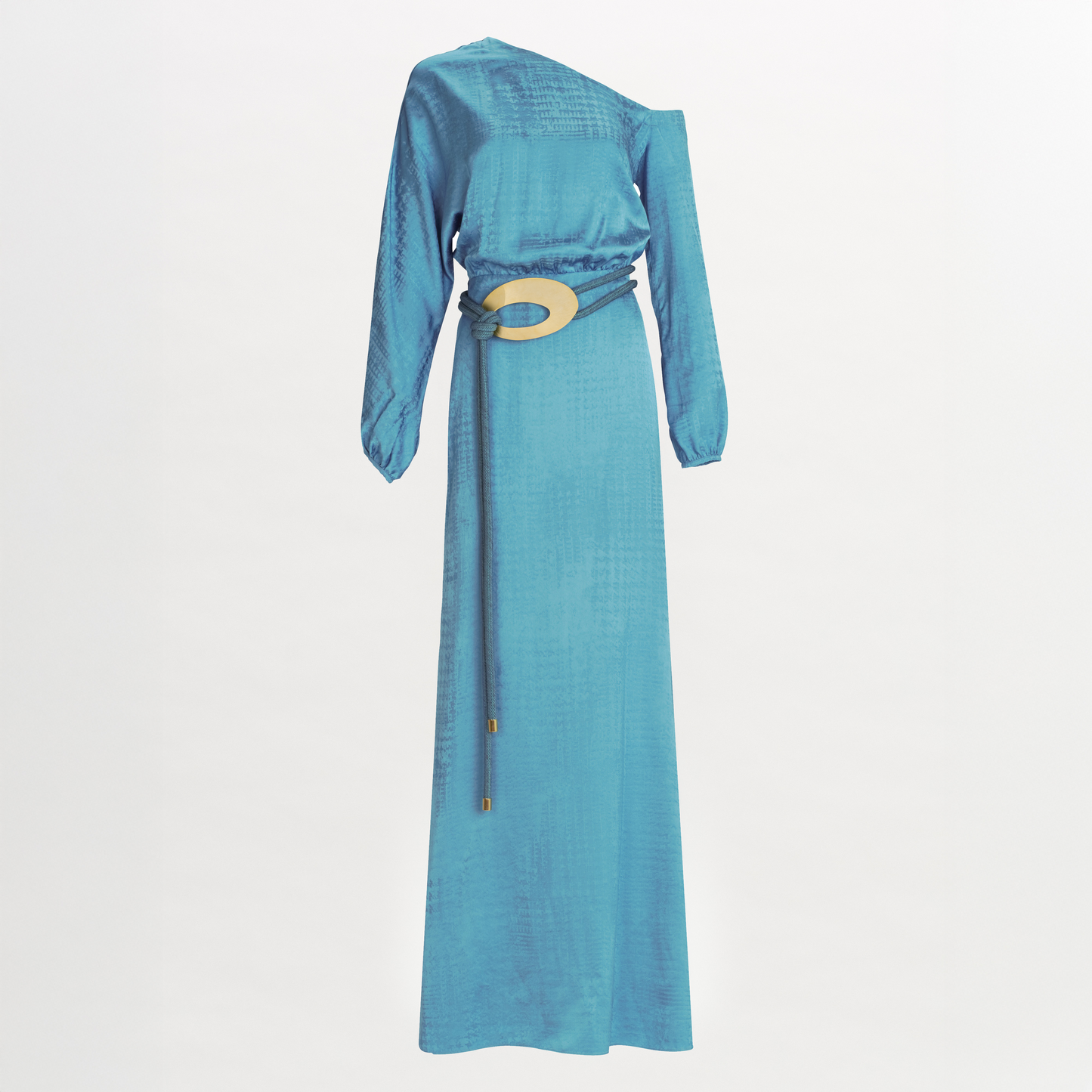 The Elga Dress is a long-sleeved, one-shoulder turquoise maxi with an asymmetric neckline, crafted from textured Italian fabric and cinched at the waist by a thin belt with a large circular buckle.