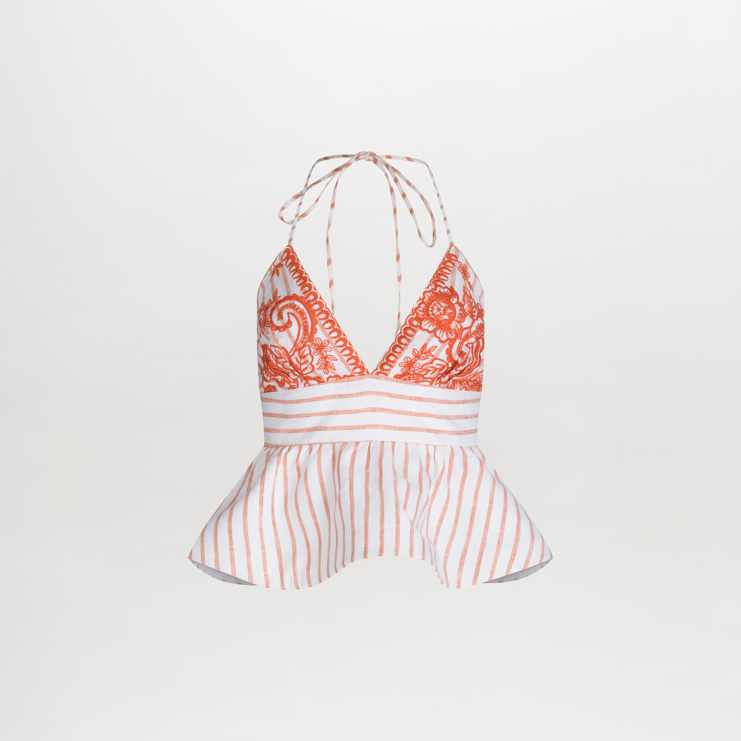 The Fabiola Blouse is a sleeveless halter top featuring embroidered paisley, vibrant orange accents, vertical stripes, and a peplum effect at the waist with elegant neck ties.