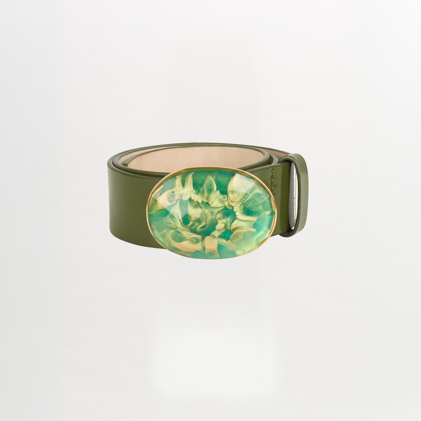 The Irene Belt Green features Italian olive green leather and a large oval buckle with green and gold resin marbling, shown coiled on a white background—ideal for updating your Fall 2023 wardrobe.