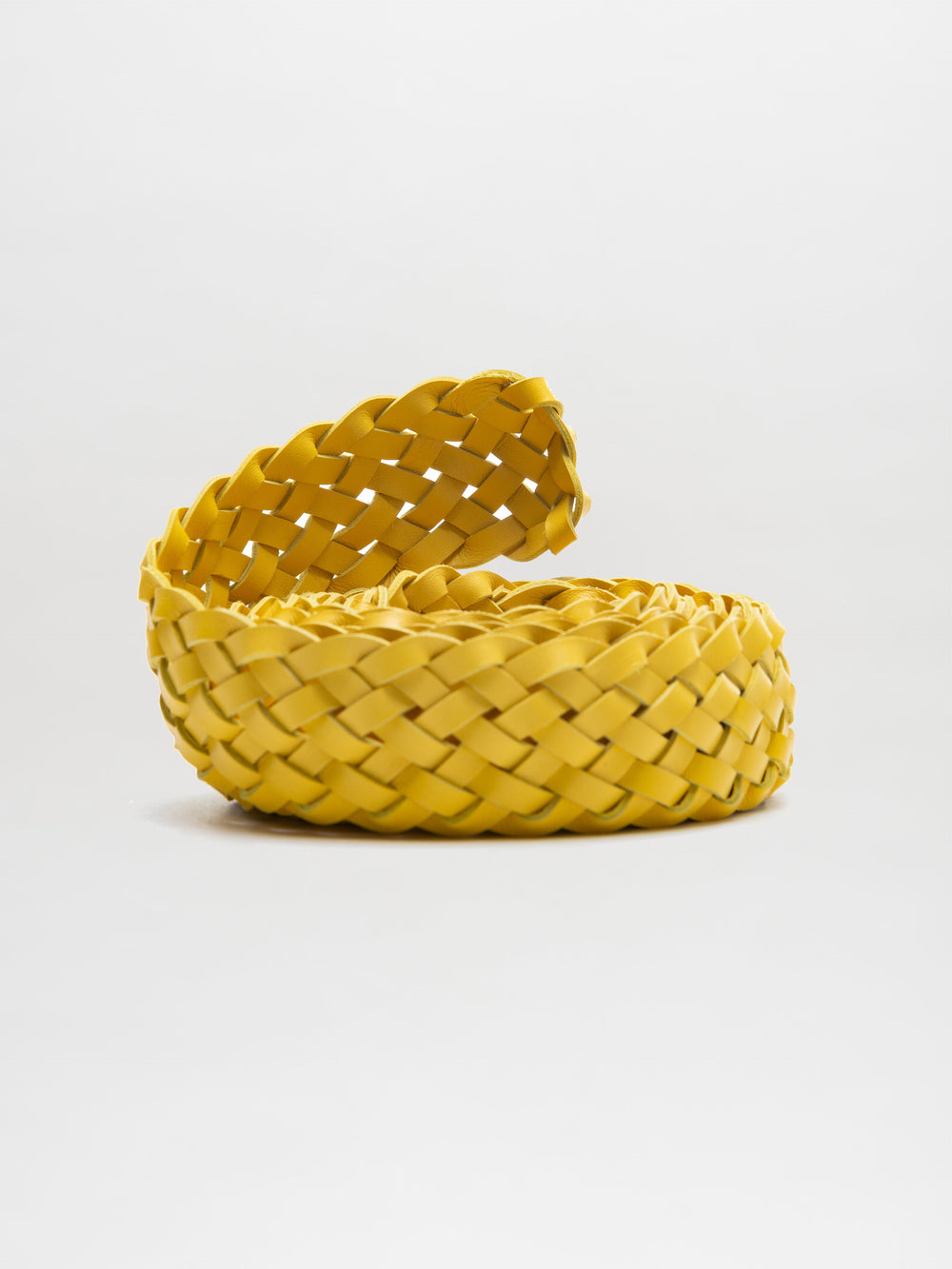 The Lauren Belt, featuring a yellow braided ribbon reminiscent of elegant Italian leather, gracefully coils on a white background.