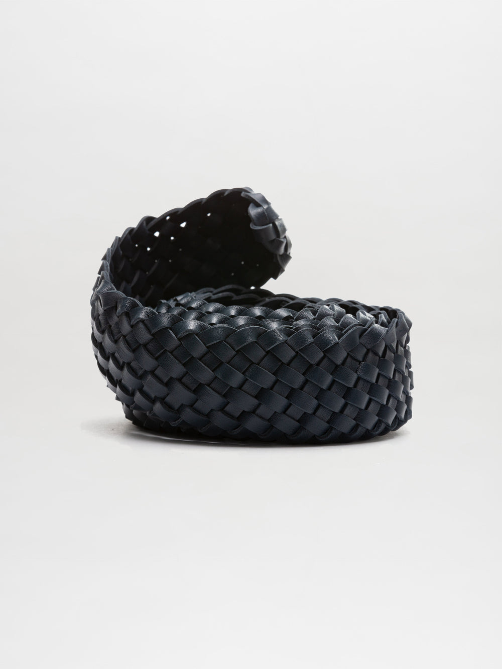 On a light gray background, the Lauren Belt, precisely crafted from dark braided leather, is rolled up.