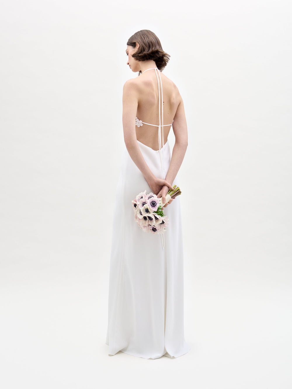 A woman in the Lua Dress holds a bouquet of flowers.