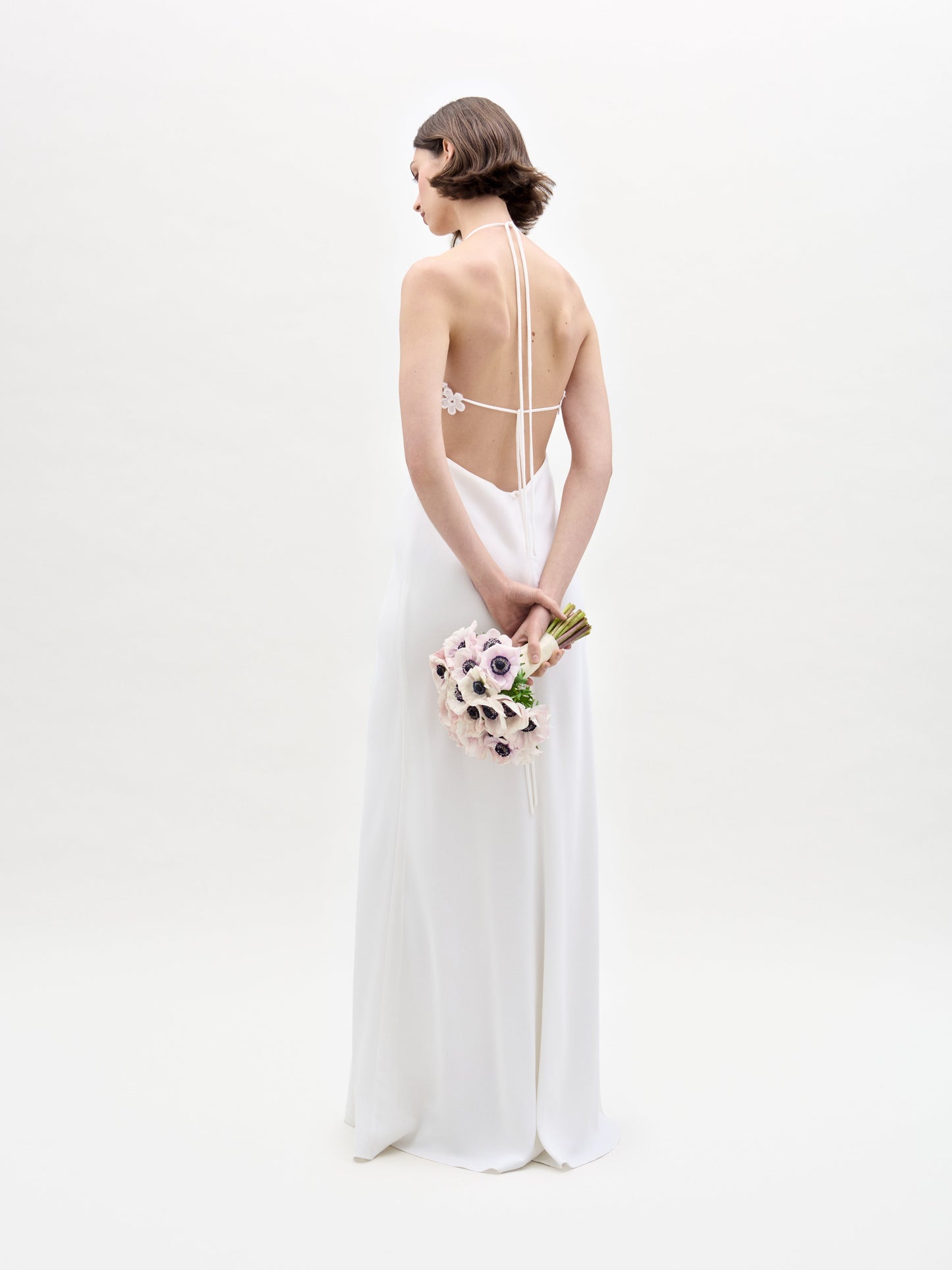 A woman in the Lua Dress holds a bouquet of flowers.