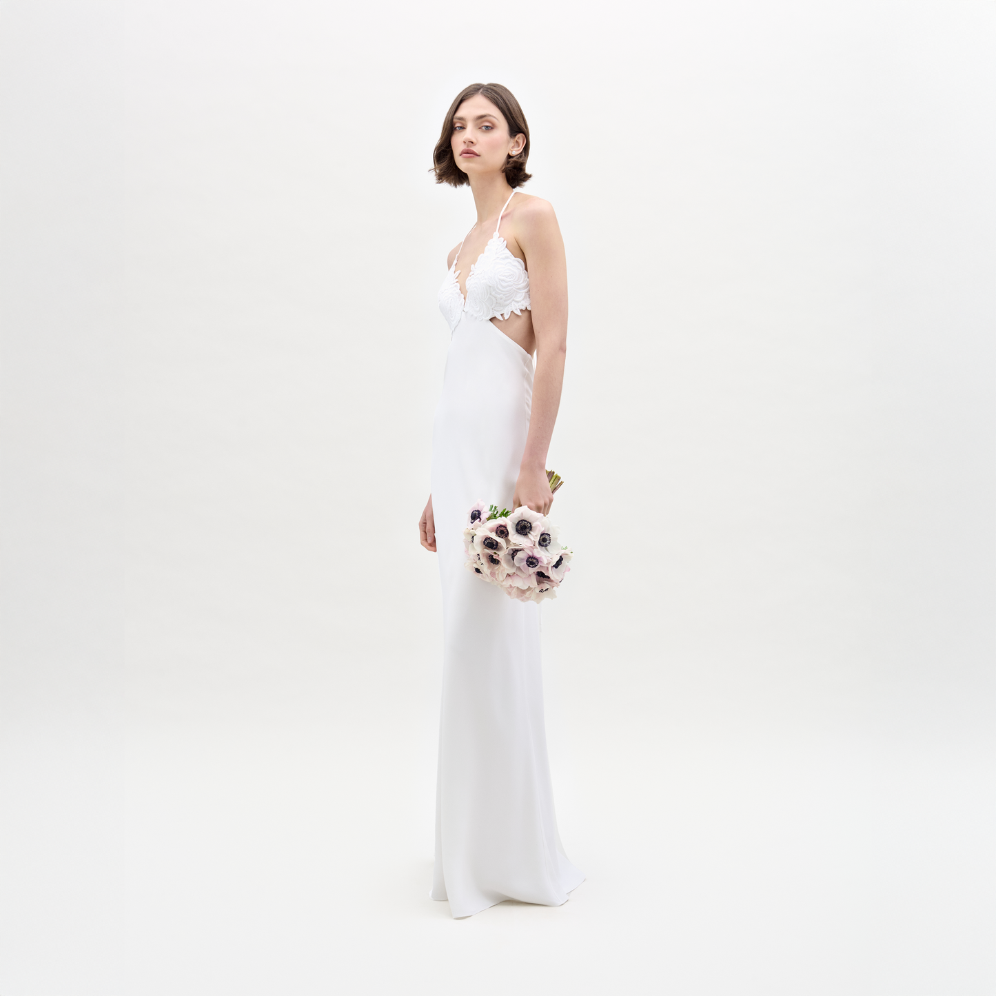 A woman in the Lua Dress holds a bouquet of flowers.