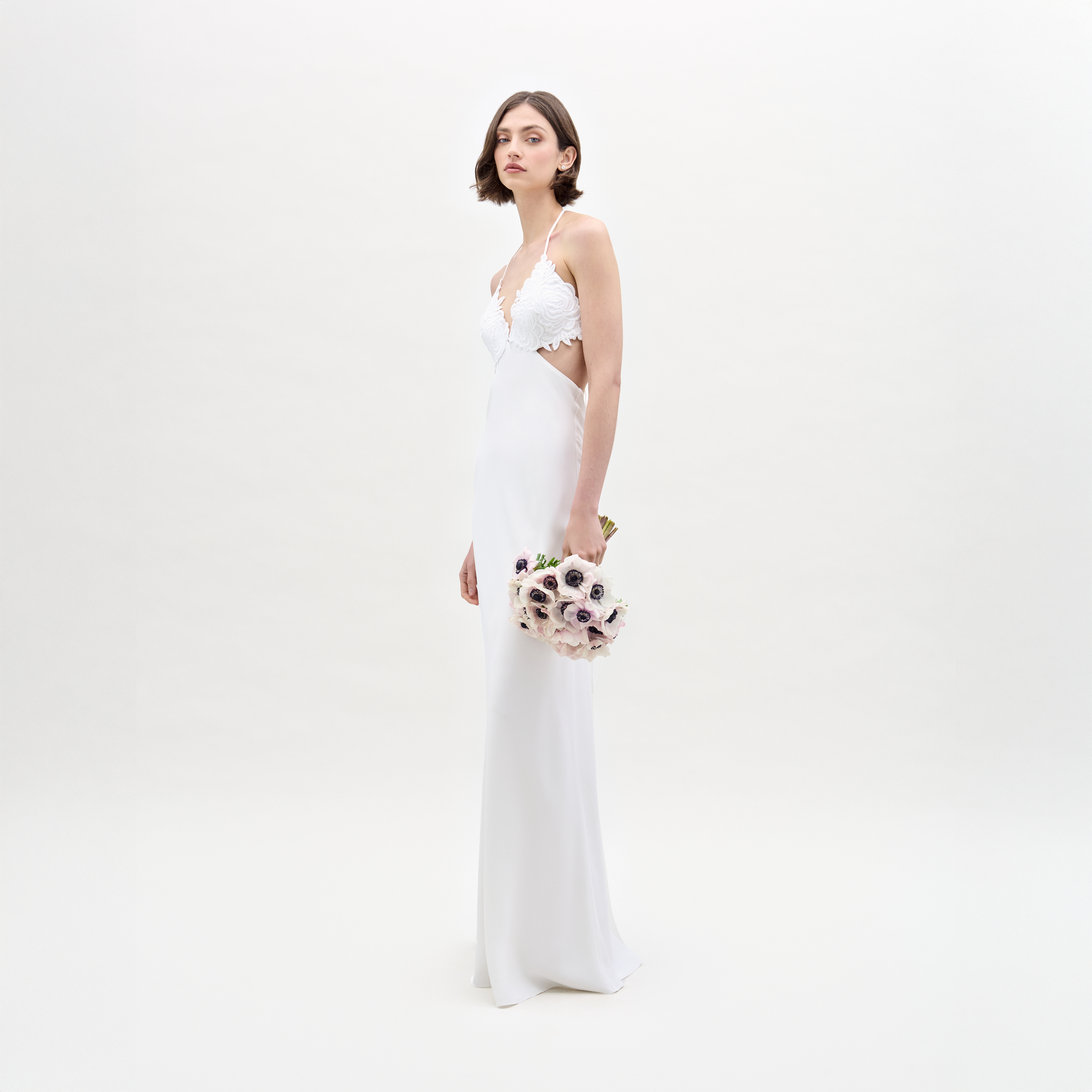 A woman in the Lua Dress holds a bouquet of flowers.