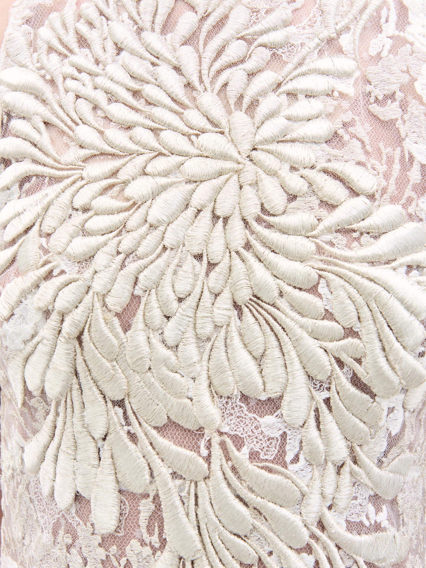 A woman models the Levi Dress, a sleeveless, floor-length maxi featuring floral embroidery and delicate appliqué, standing against a plain white background.