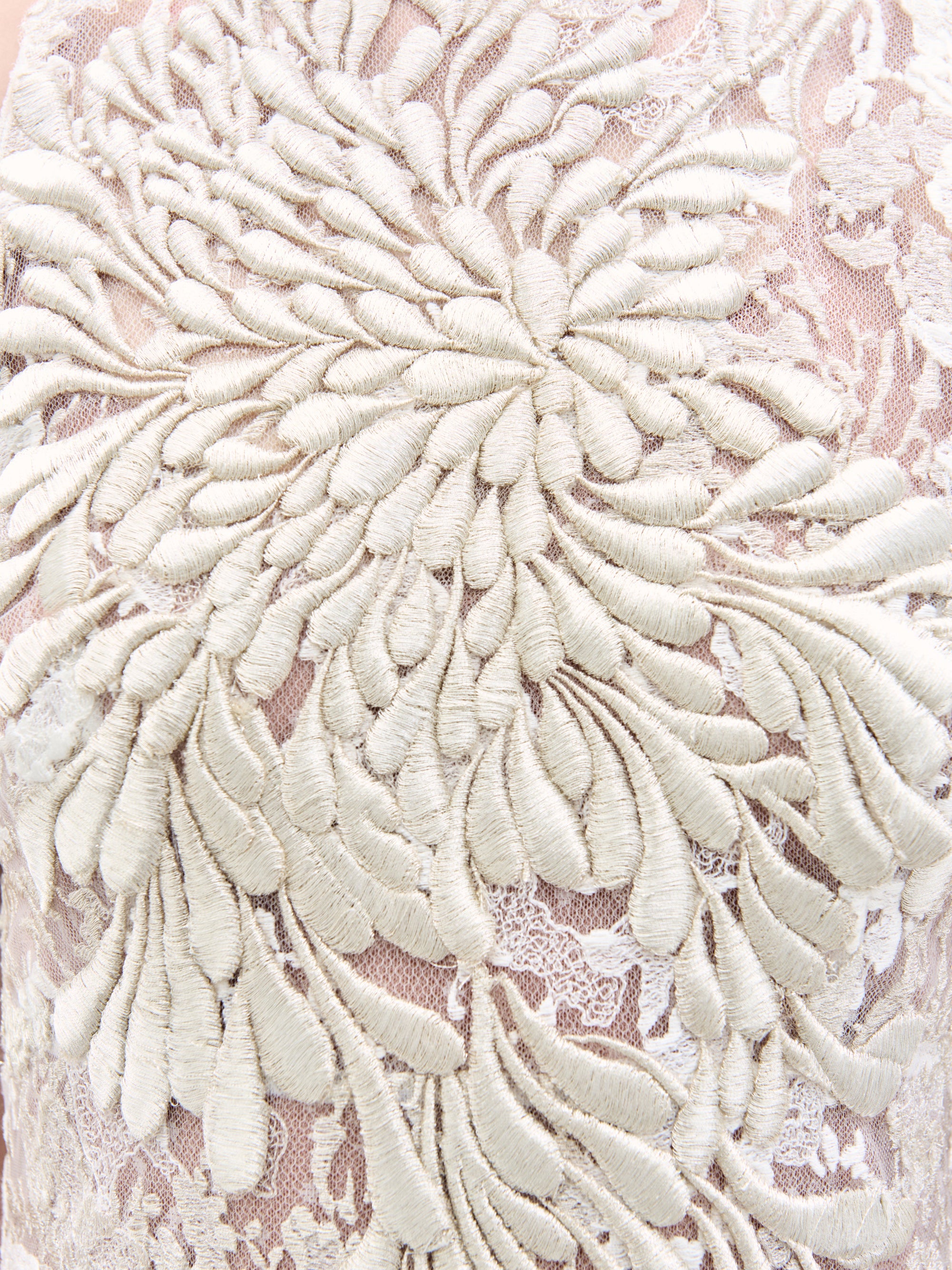 A woman models the Levi Dress, a sleeveless, floor-length maxi featuring floral embroidery and delicate appliqué, standing against a plain white background.