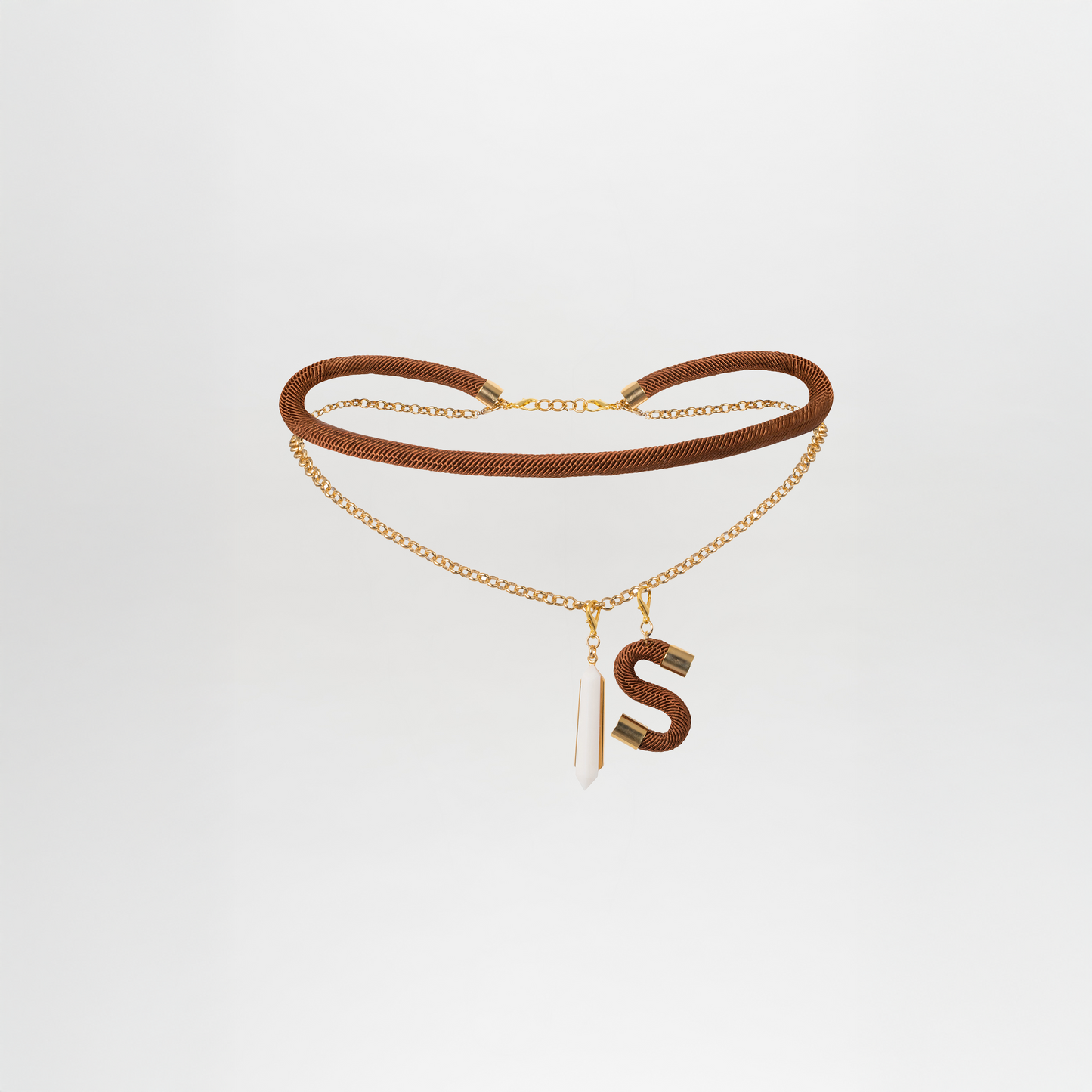 The Mireya Belt showcases a stunning combination of brown and gold with a hanging letter "S" and a shimmering white crystal pendant made from Petralux® fantasy stone, set against a pure white background.