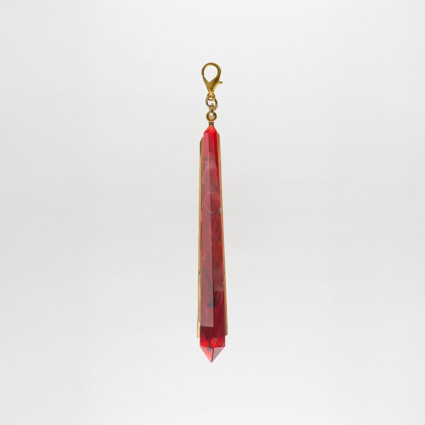 The Montse Charm is a red, faceted Petralux® fantasy stone pendant with a gold clasp, shown hanging vertically against a plain white background.