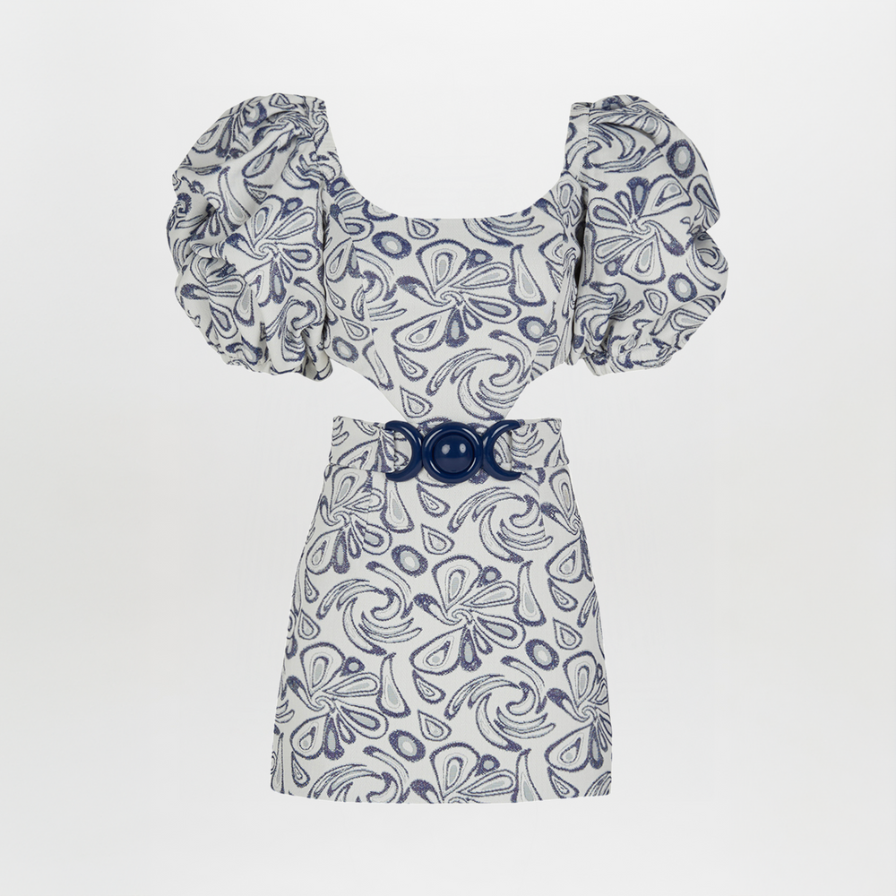 The Marlin Dress Navy Swirls from the Spring 2023 collection is a short white dress adorned with blue abstract patterns, featuring puffed sleeves and a wide navy belt with a large circular buckle.