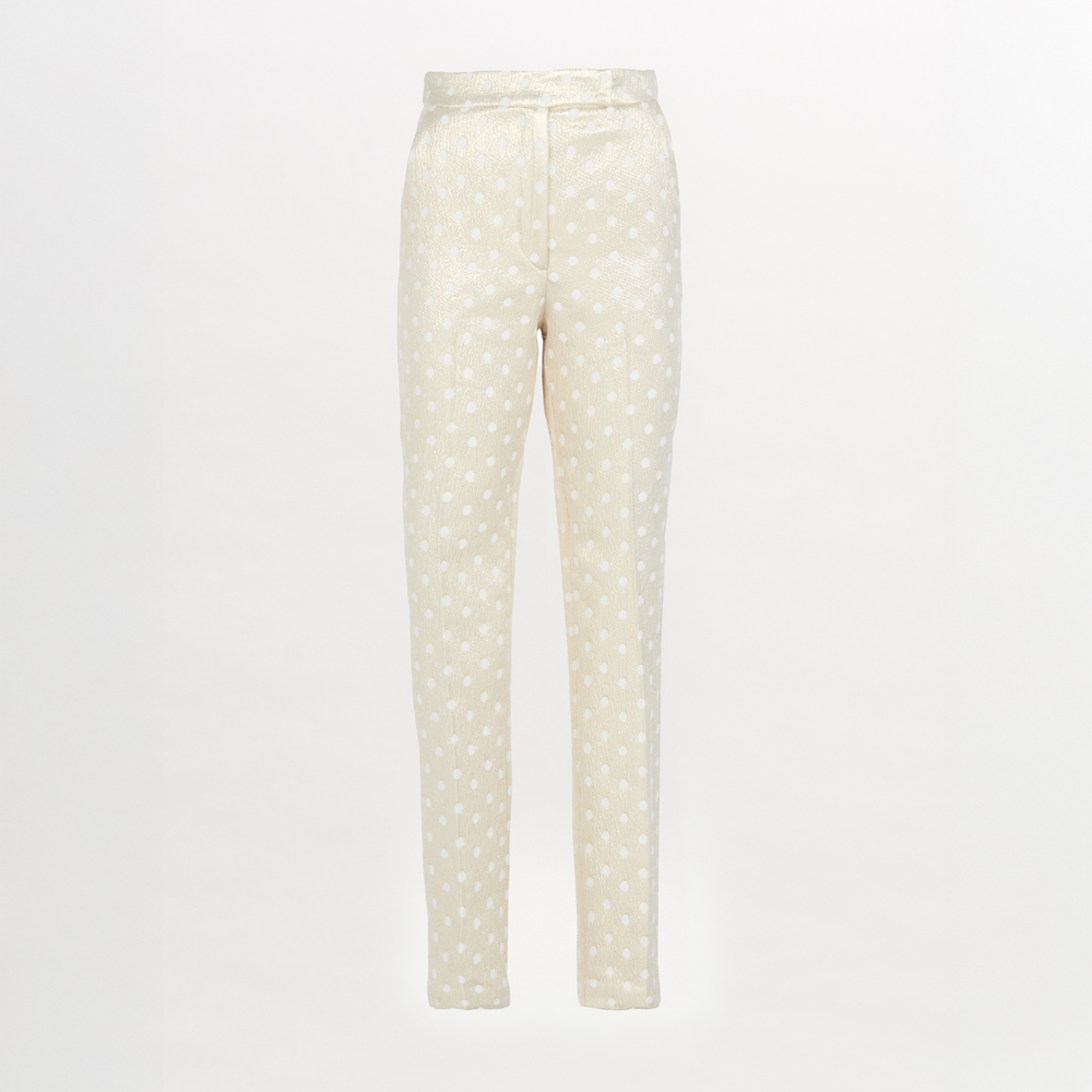 Rear view of a person with long hair in a ponytail, wearing a white blouse and the Orion Pant Gold Inverted, featuring high-waisted trousers with a straight leg silhouette, standing in heels on a plain background.