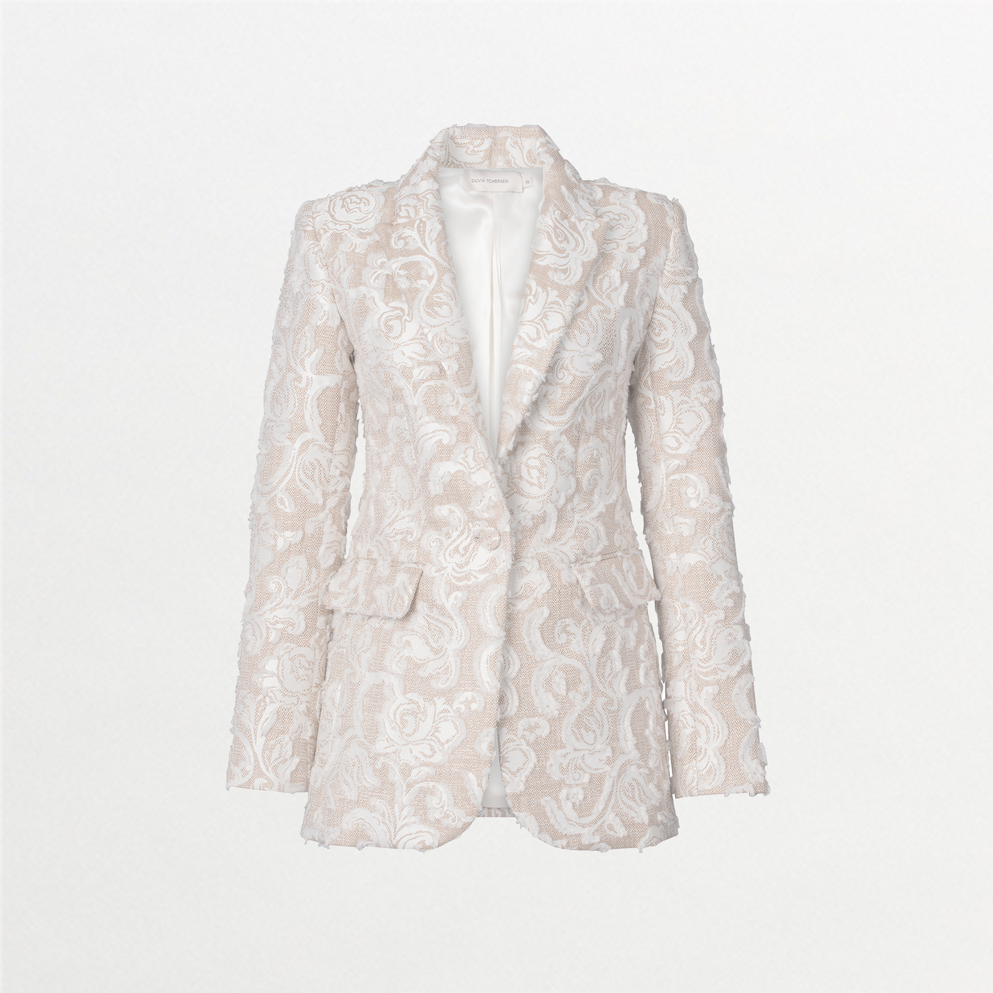 A person with slicked-back hair wears the Rebeca Jacket in Abstract White Floral and matching pants, looking to the side against a blue background. Mark your calendars for September 2nd, 2024; outfits like this will ship between August 19th and that date.