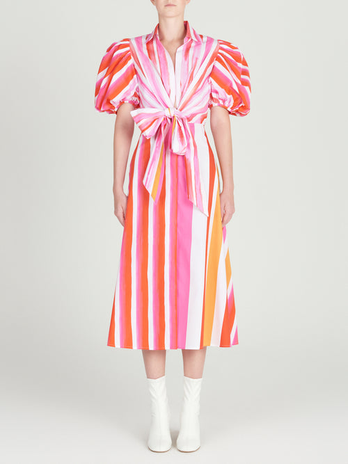 A Pavia Dress Rouge Orange Stripes with a brushstroke stripe print and a bow.