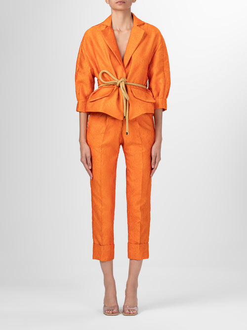A women's Gianna Jacket Orange Petal with a belt, featuring a relaxed fit.