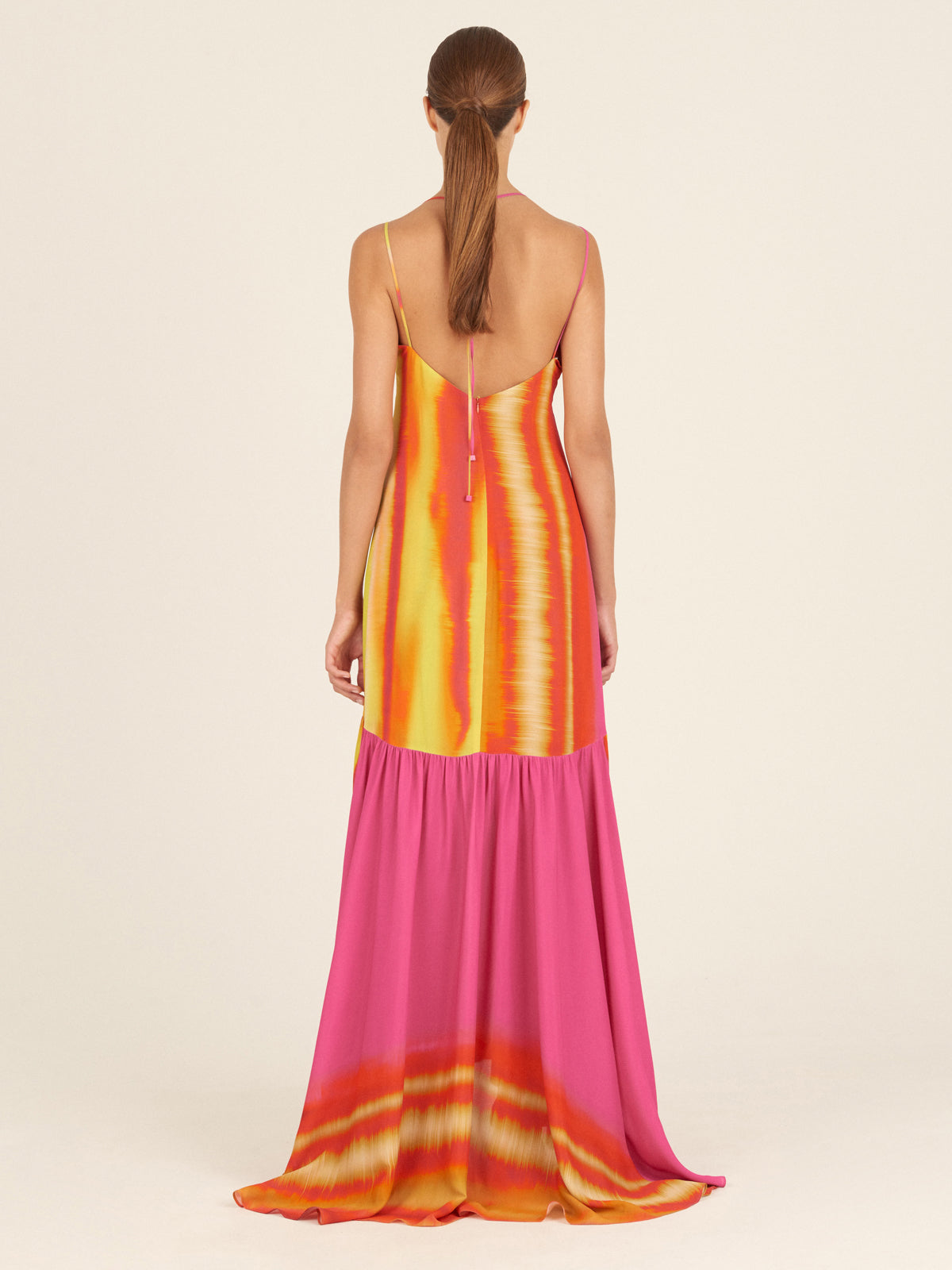 A person wearing the Eva Dress Fuschia Lime Stripes—a vibrant creation featuring a v-neck, cut-out waist, and flared skirt—stands against a plain background. Perfect for Spring 2023, this ensemble captures vibrant style with its delightful hues.