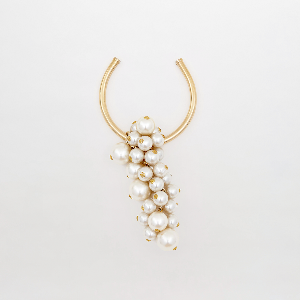 Introducing the Shania Necklace Pearl: a gold U-shaped necklace embellished with an array of white pearls in various sizes, elegantly draping in a cascading formation. Available for pre-order now to ensure delivery by February 15th.