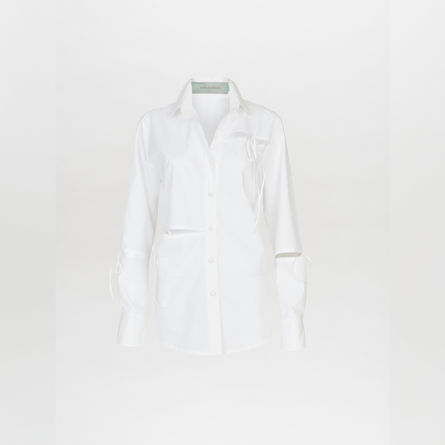 The Simona Blouse White features a classy silhouette with long sleeves, a collar, front pocket, and tailored cut-out sleeve details, shown against a plain white background.