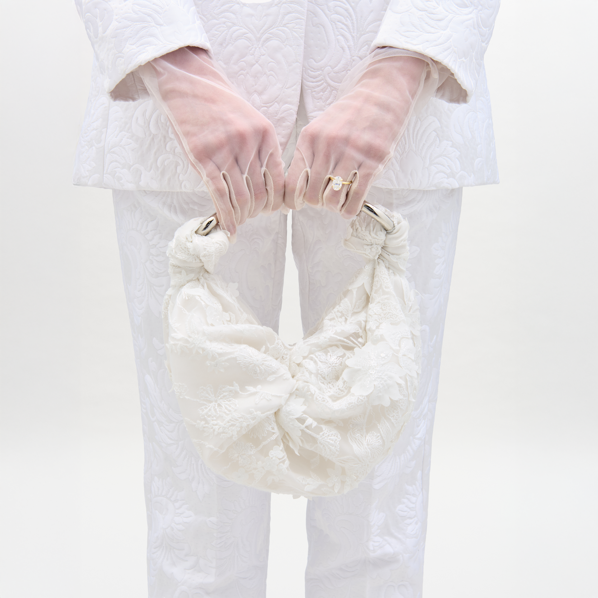 The Sofia Bag Small is a white handbag with an embroidered tulle lace overlay, gold-toned curved handle, and gathered fabric details, displayed against a plain light background.