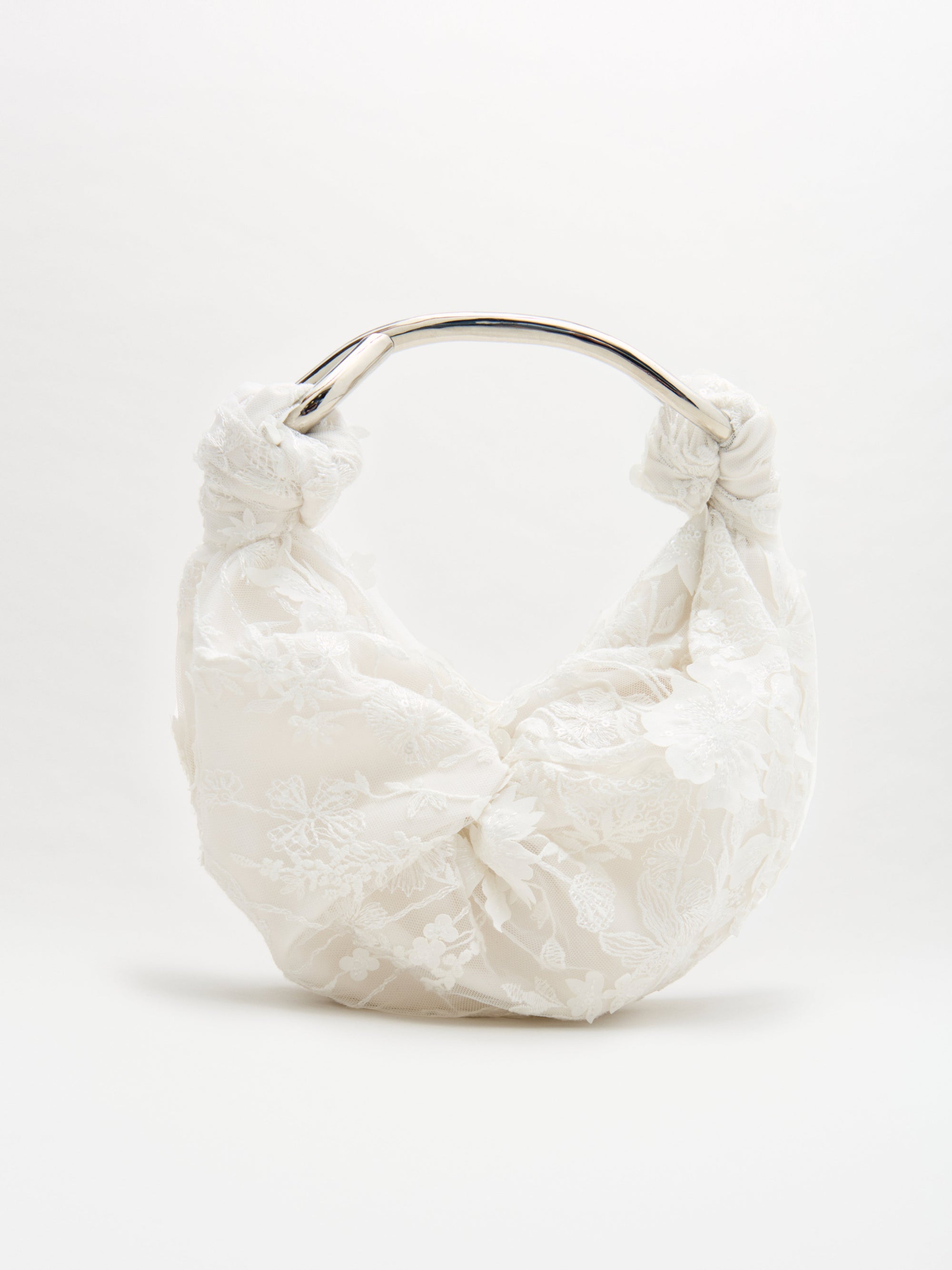 The Sofia Bag Small is a white handbag with an embroidered tulle lace overlay, gold-toned curved handle, and gathered fabric details, displayed against a plain light background.