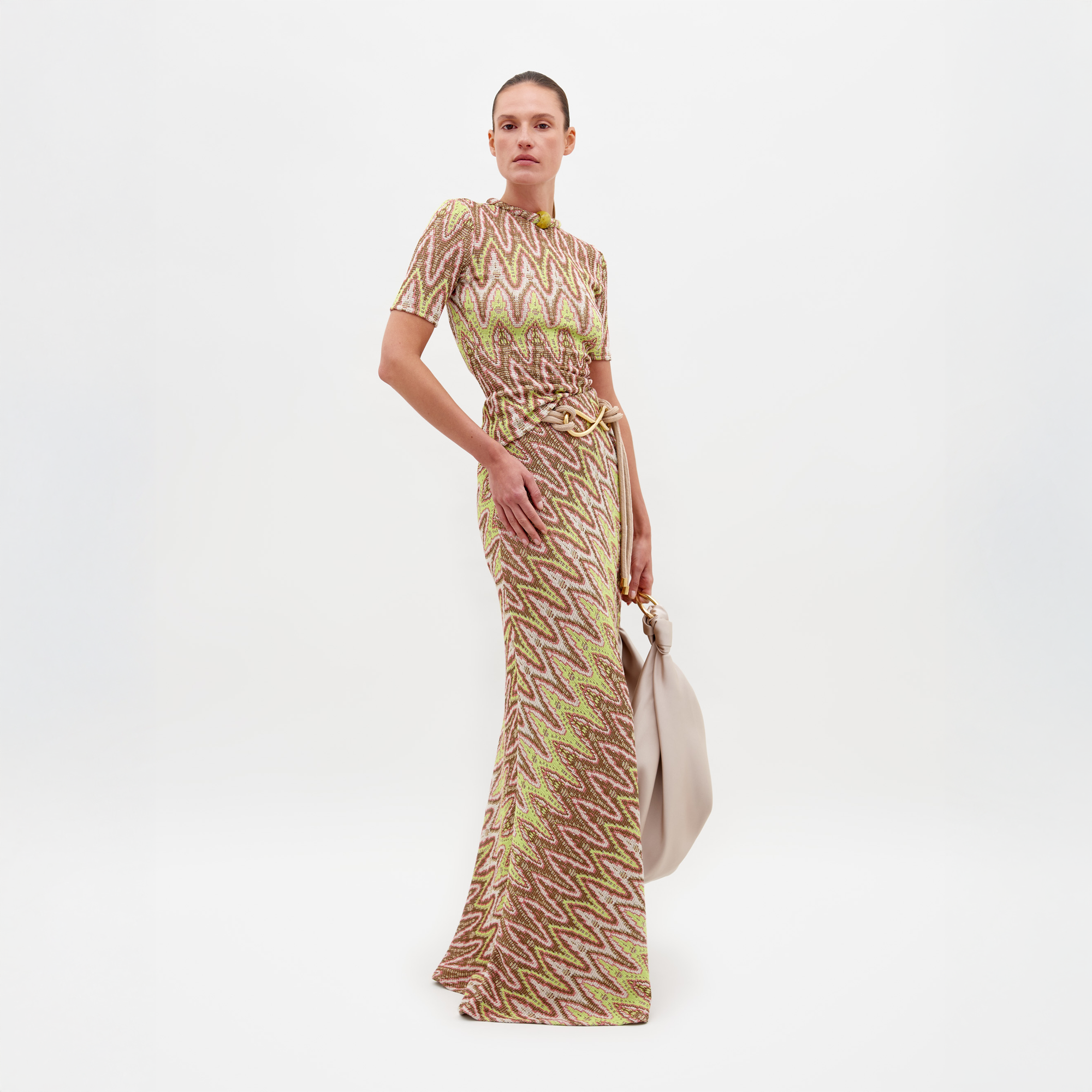 A person wearing the Famara Skirt Zigzag Neon, styled with a light-colored bag against a plain white background. Available for pre-order now; ships by February 15th, 2025.