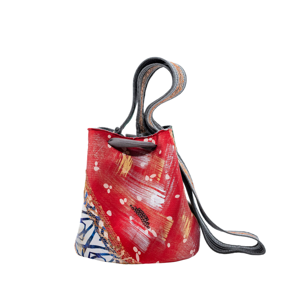 A patterned Mochila Laaput Abstract Grey handbag with a bow, featuring pastel and earth tones on a white background.