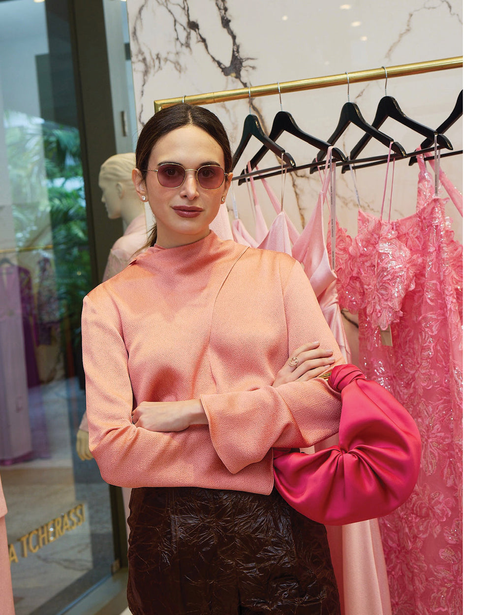 Sofia Tcherassi in a pink blouse and sunglasses standing in front of a rack of dresses at the Bal harbour boutique