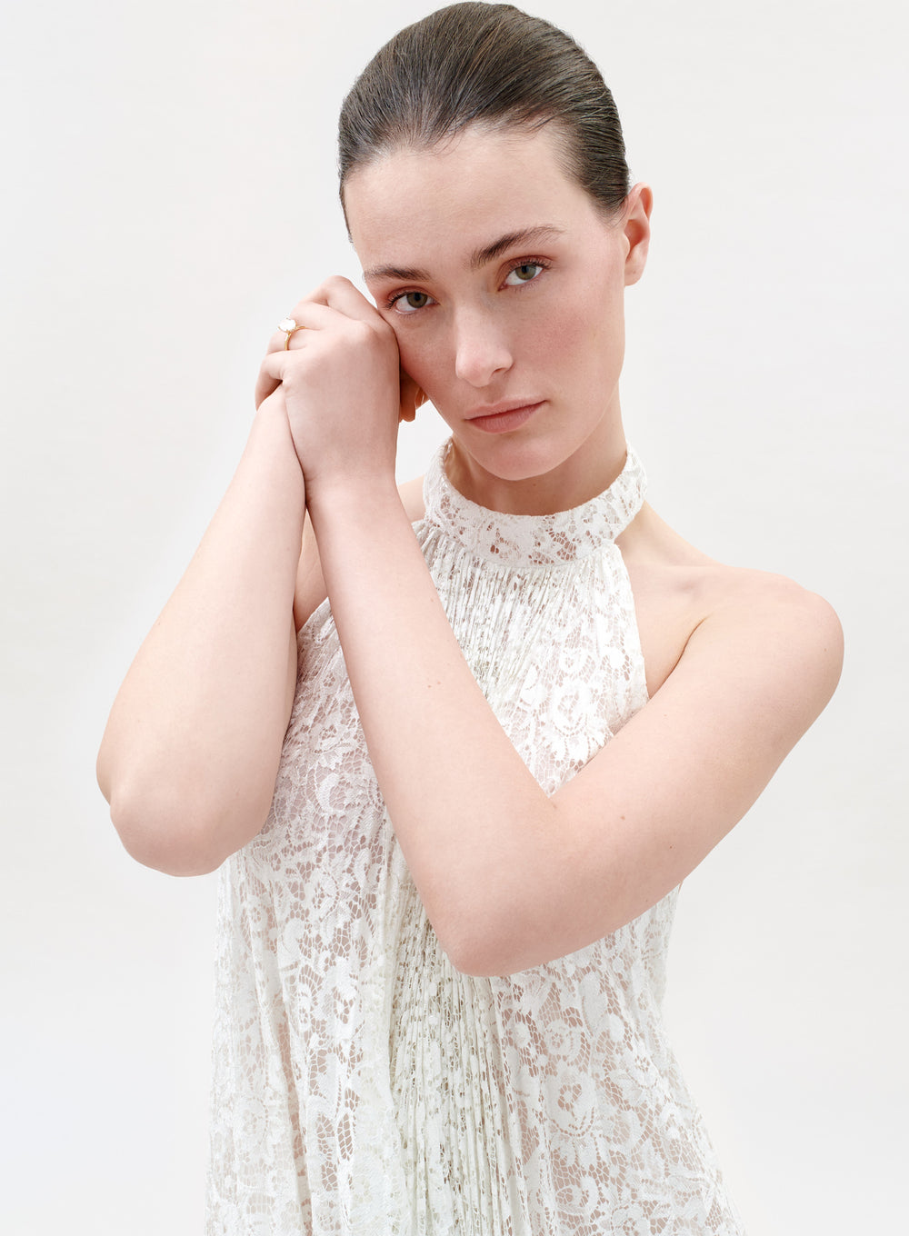Woman wearing a white lace dress against a plain background