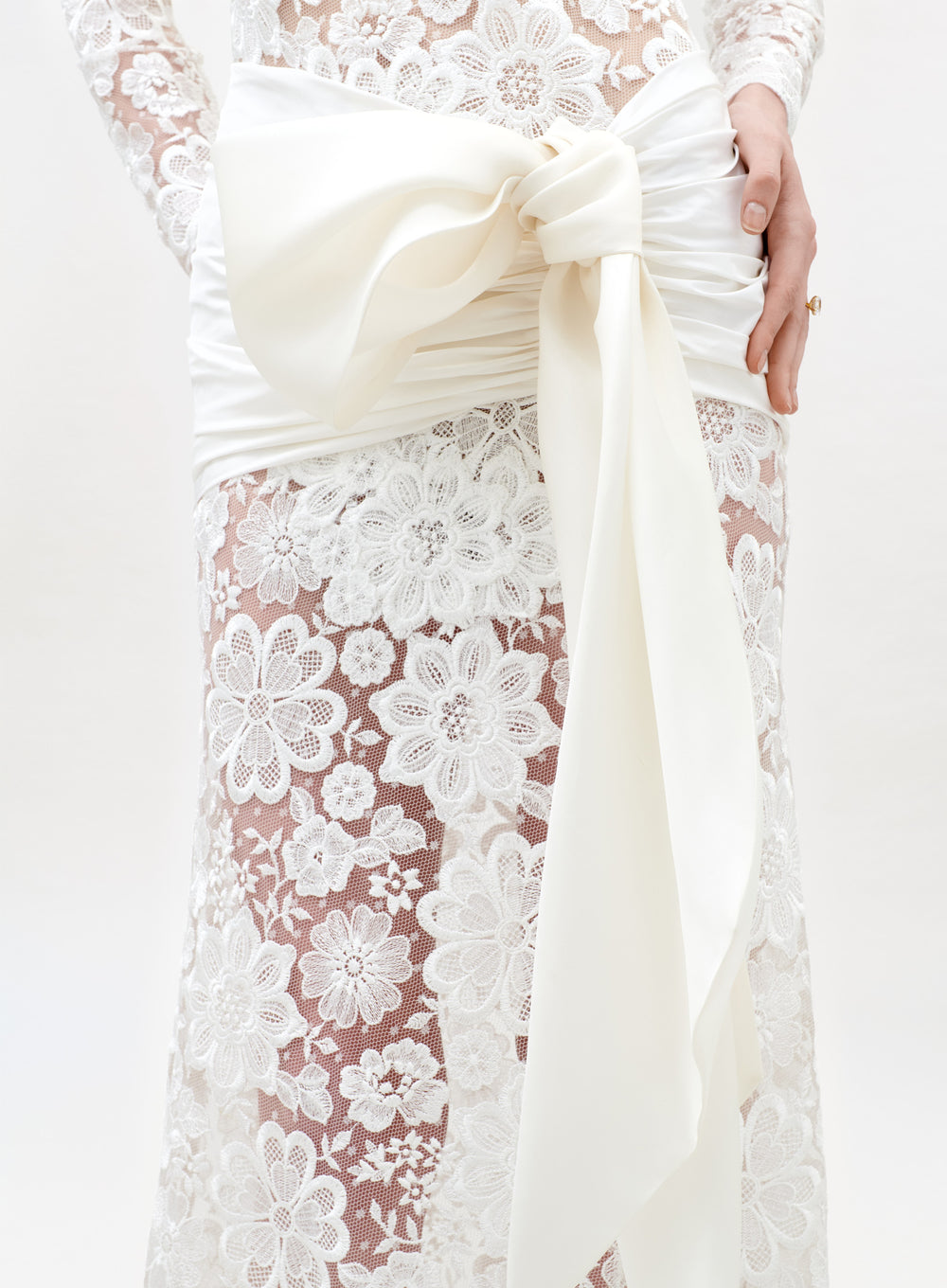 Close-up of a white lace dress with a large bow on a white background