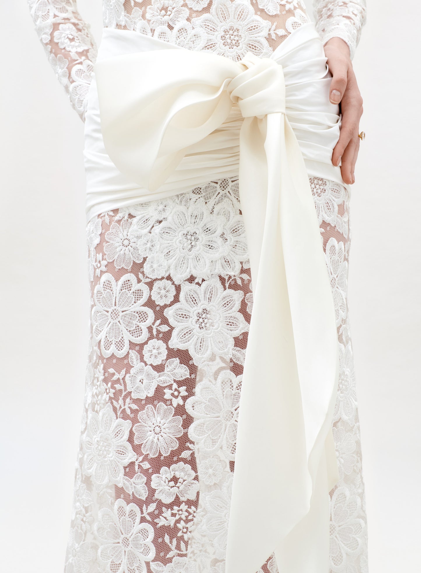 Close-up of a white lace dress with a large bow on a white background