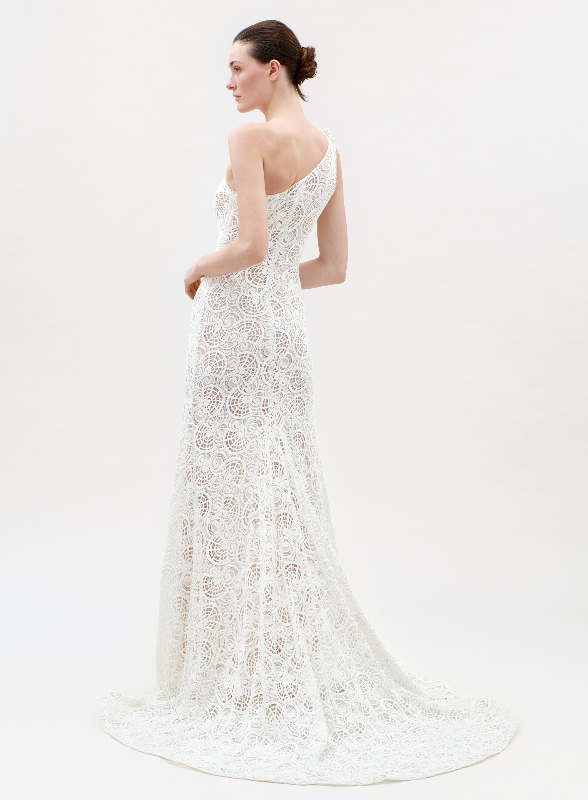 Woman wearing a white lace wedding dress on a white background
