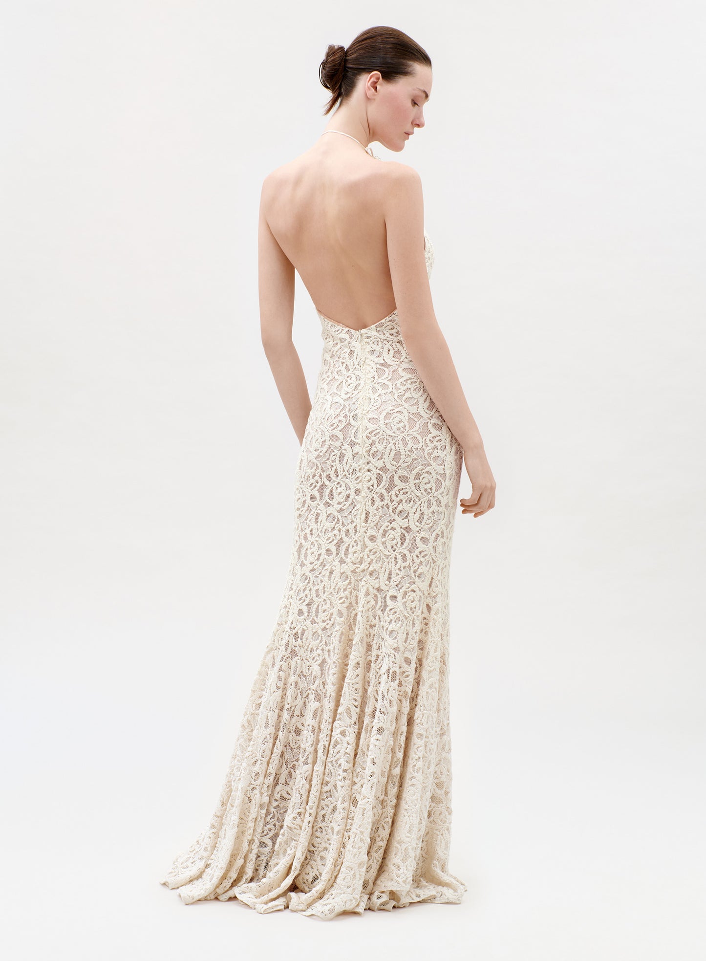Woman wearing a long, elegant dress with a lace design on a white background