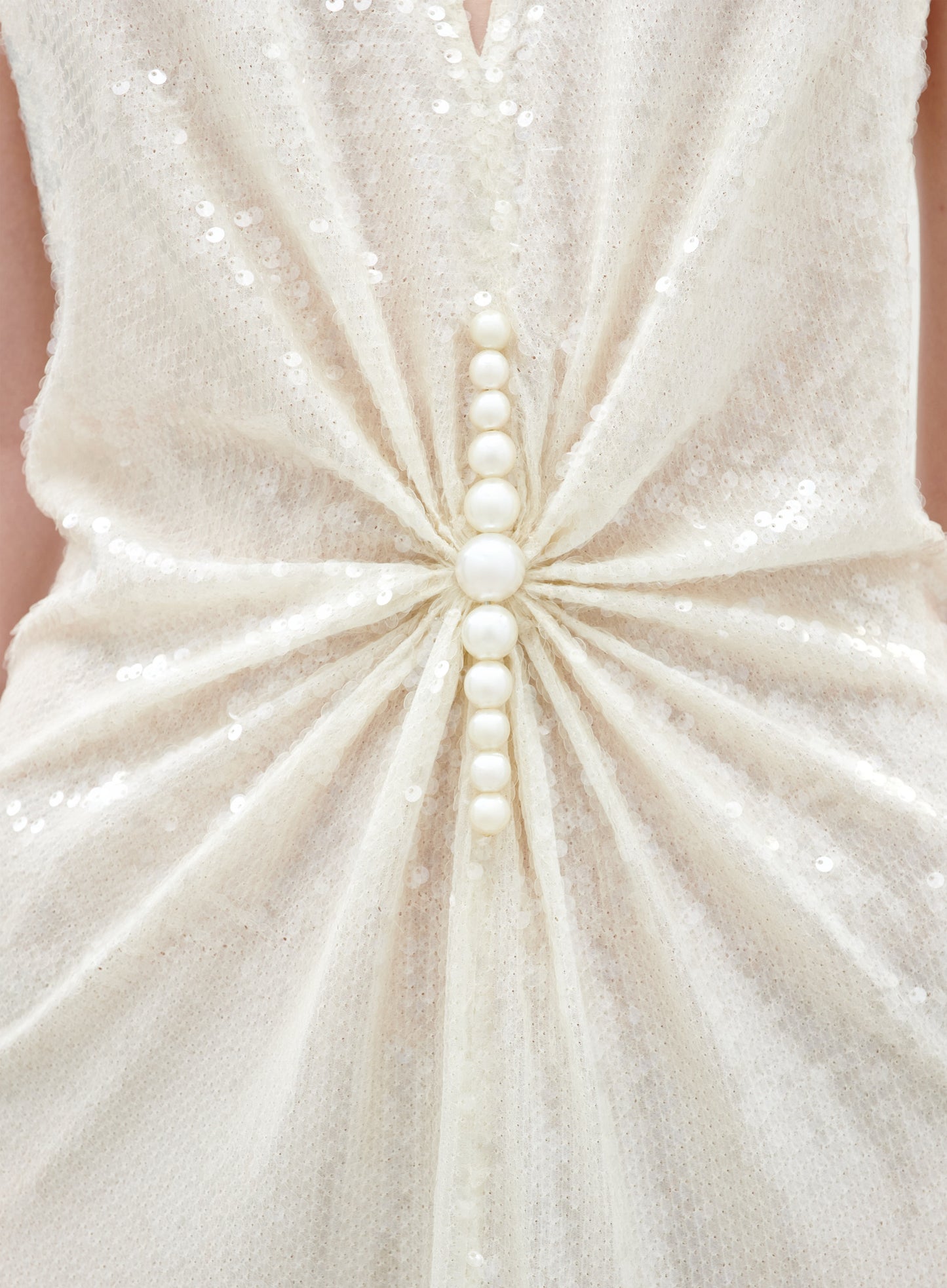 Close-up of a white sequined dress with a detailed pattern.